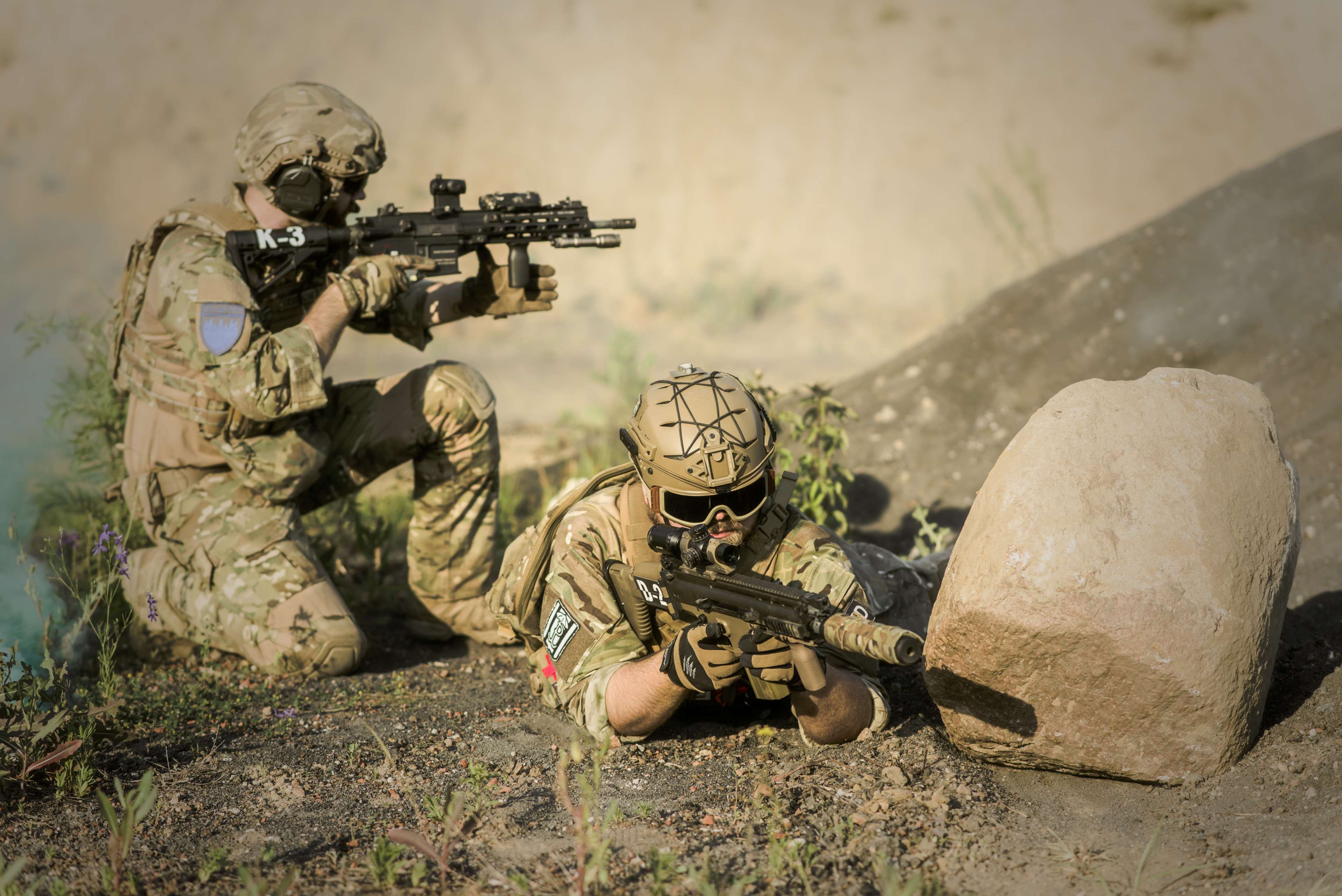 Soldiers in camouflage with rifles in a desert landscape HD Wallpaper