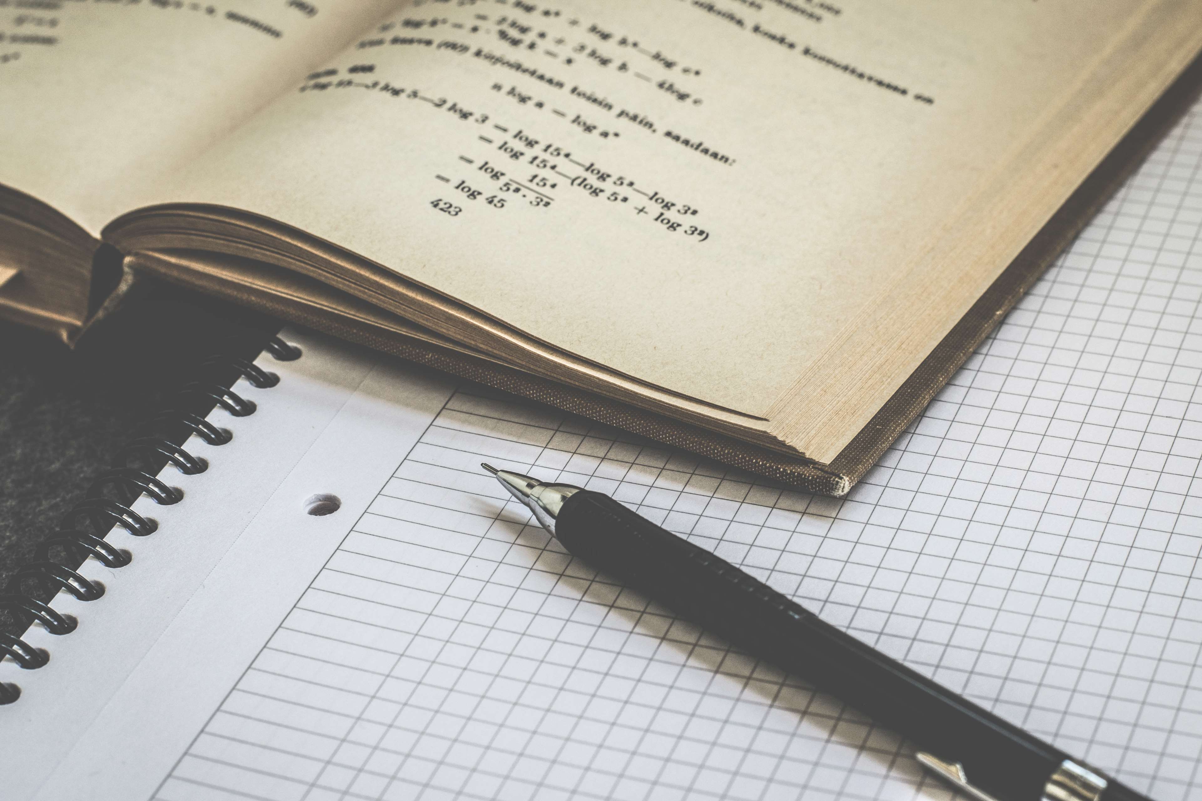 Open book with math equations and pen on graphing paper HD Wallpaper
