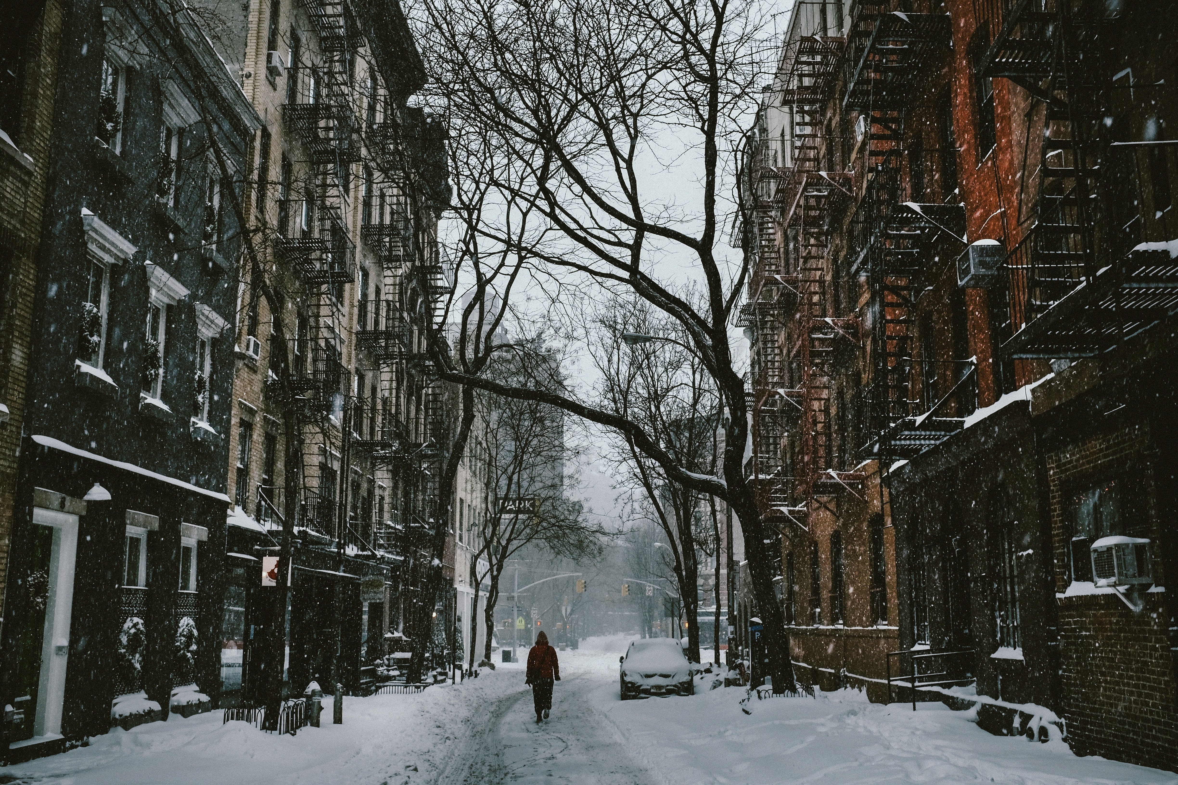 Person walking down a snowy street in a city HD Wallpaper