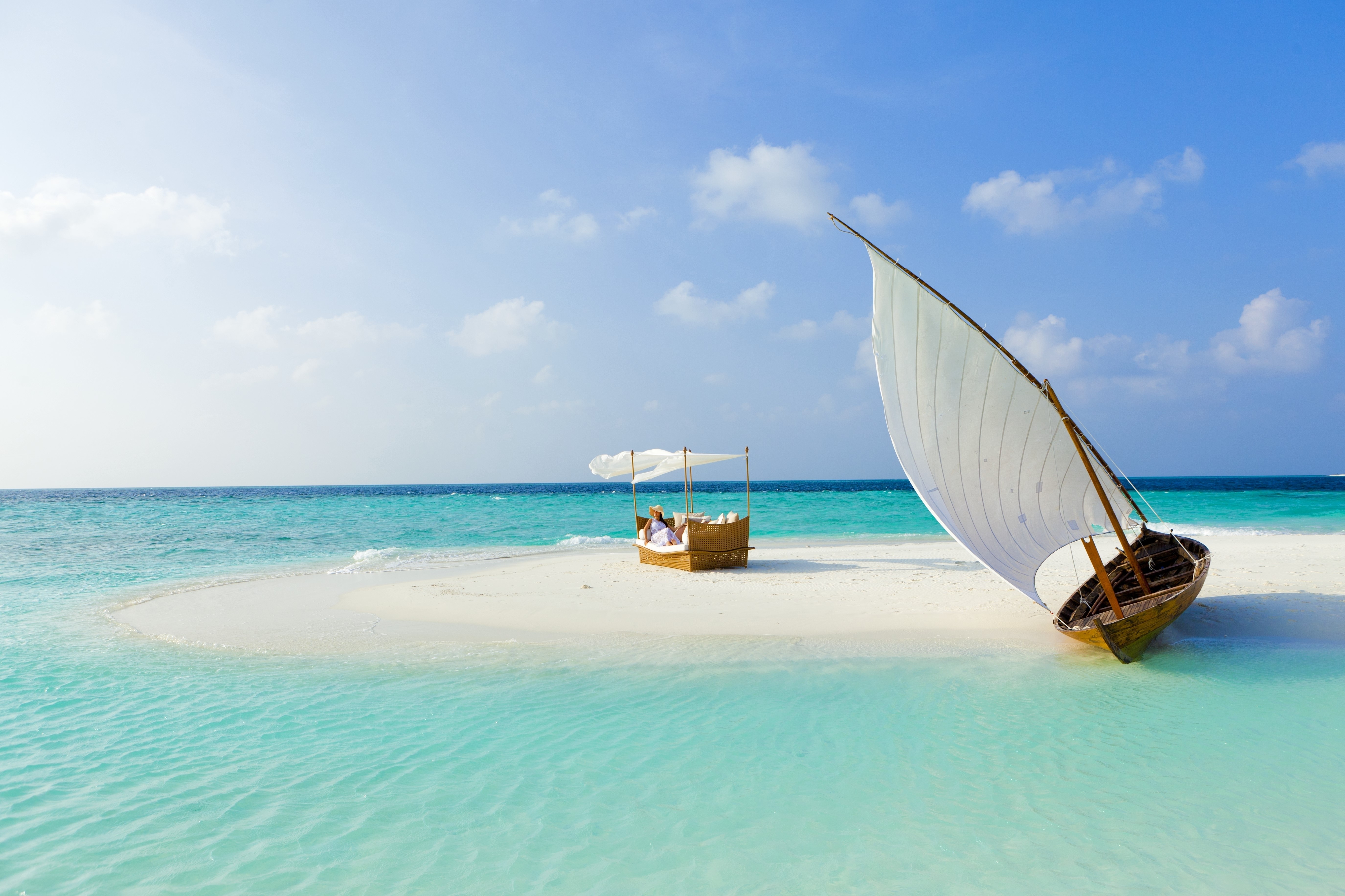 Couple relaxing on a tropical island with a sailboat HD Wallpaper