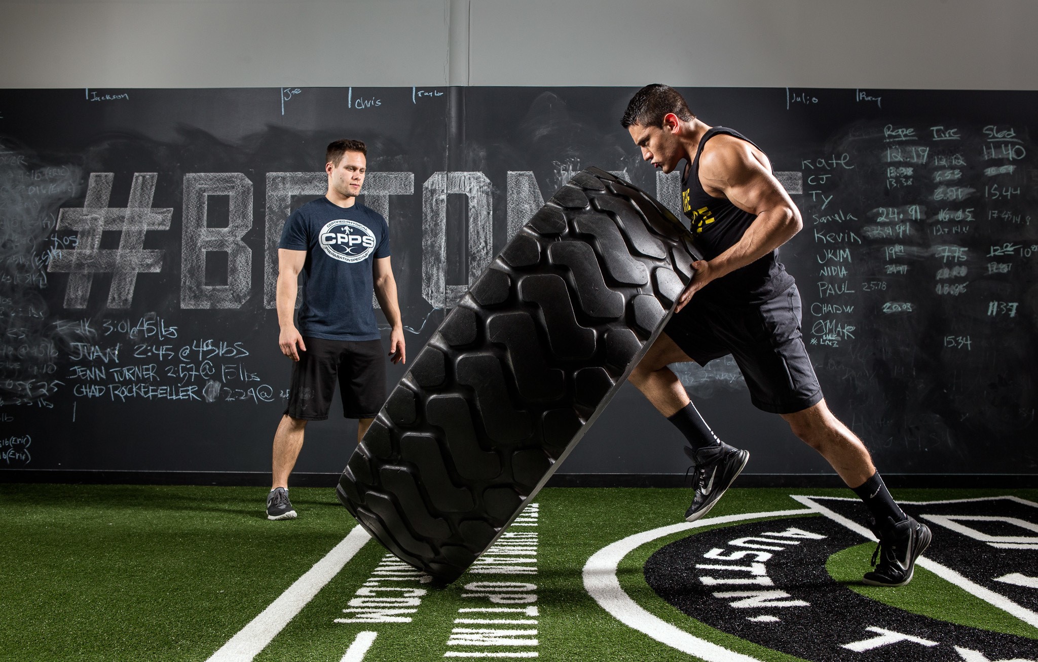 Athletes performing tire flips in a gym HD Wallpaper