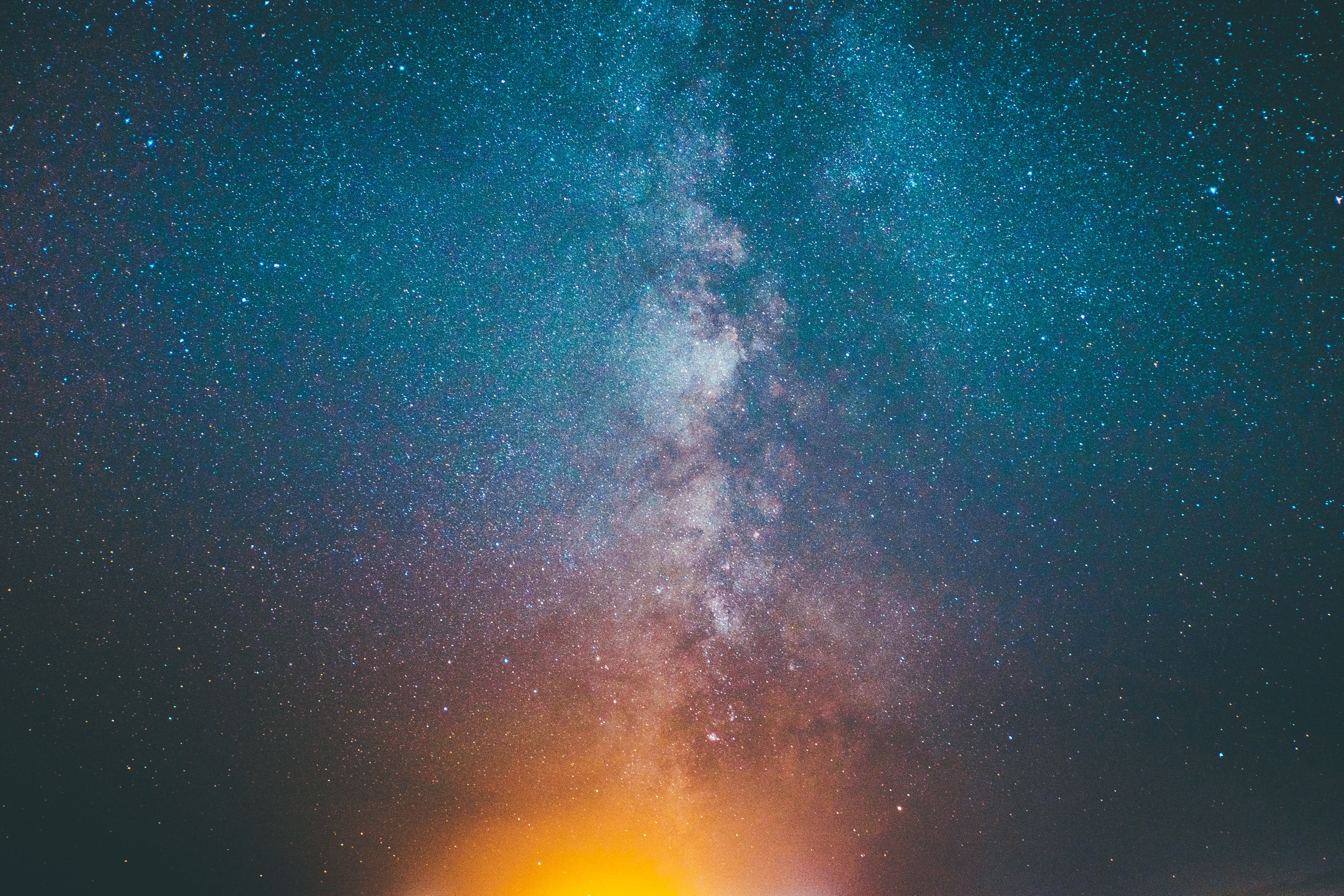 Milky Way galaxy with stars and orange glow HD Wallpaper
