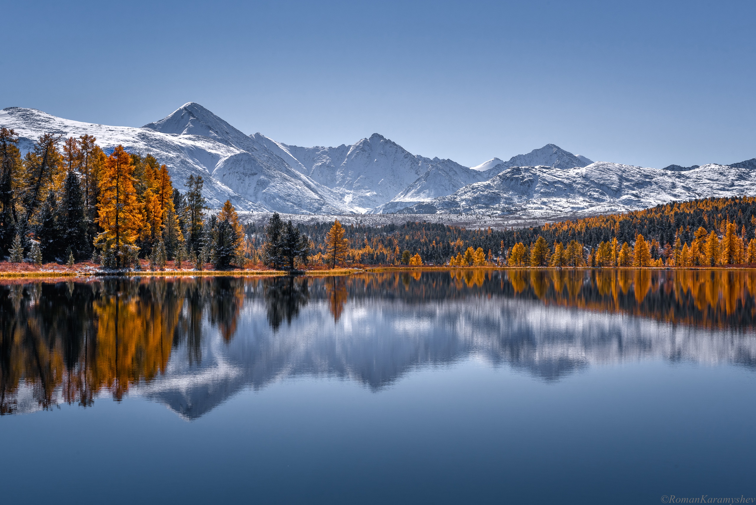 Autumn forest and snow-capped mountains reflected in a calm lake HD Wallpaper