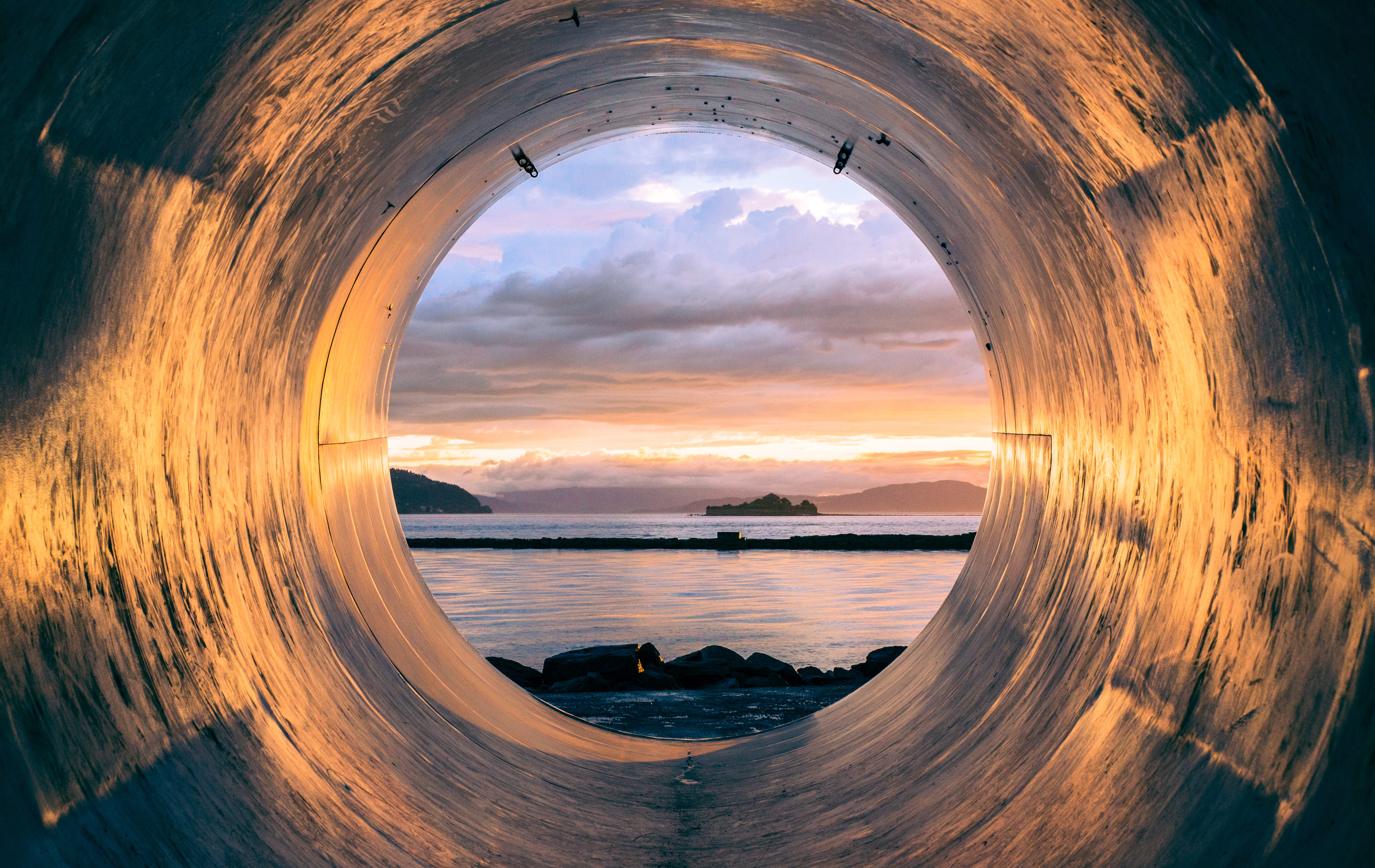 View of sunset over water through a pipe HD Wallpaper