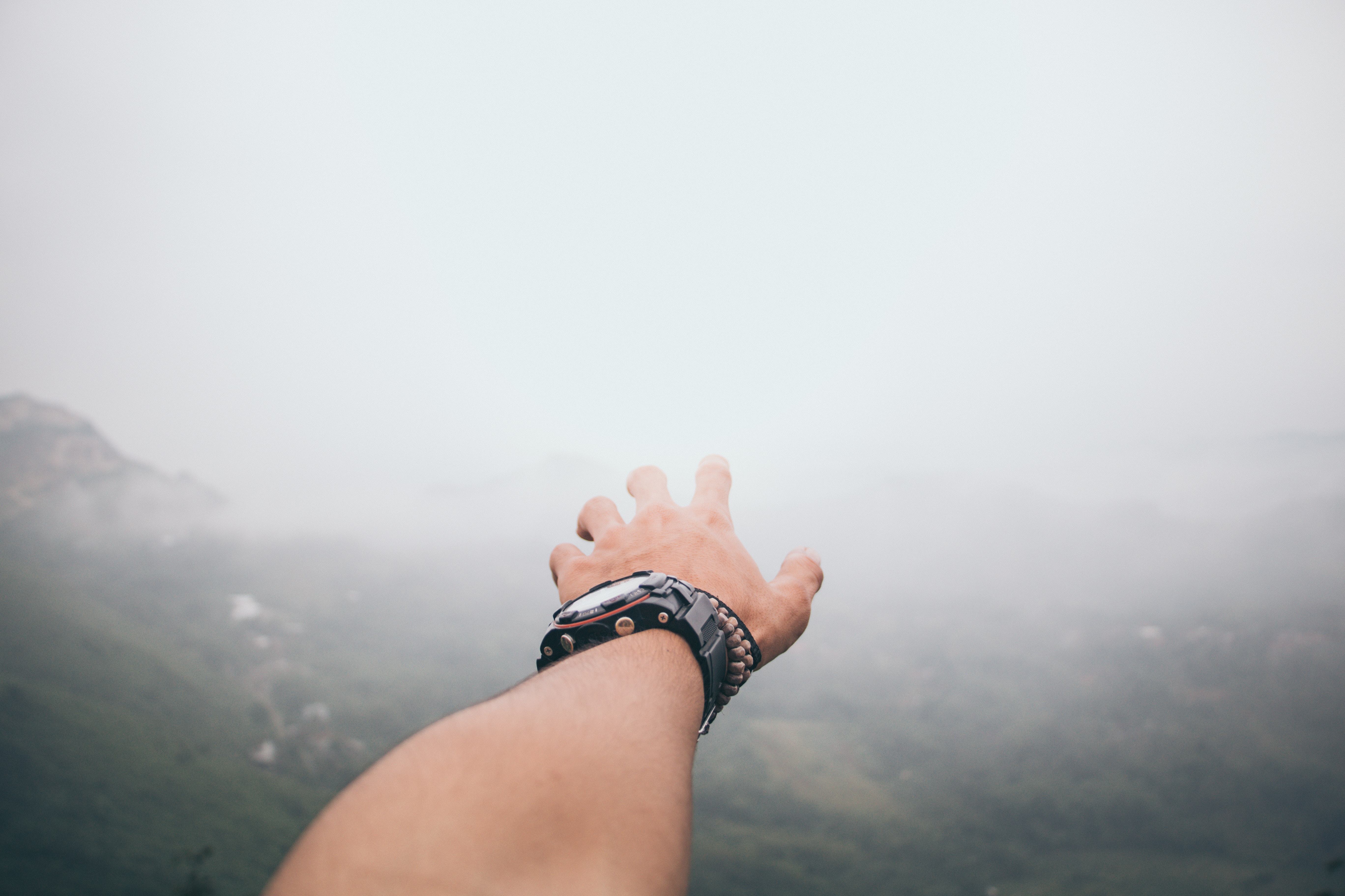 Hand reaching out over foggy mountains HD Wallpaper