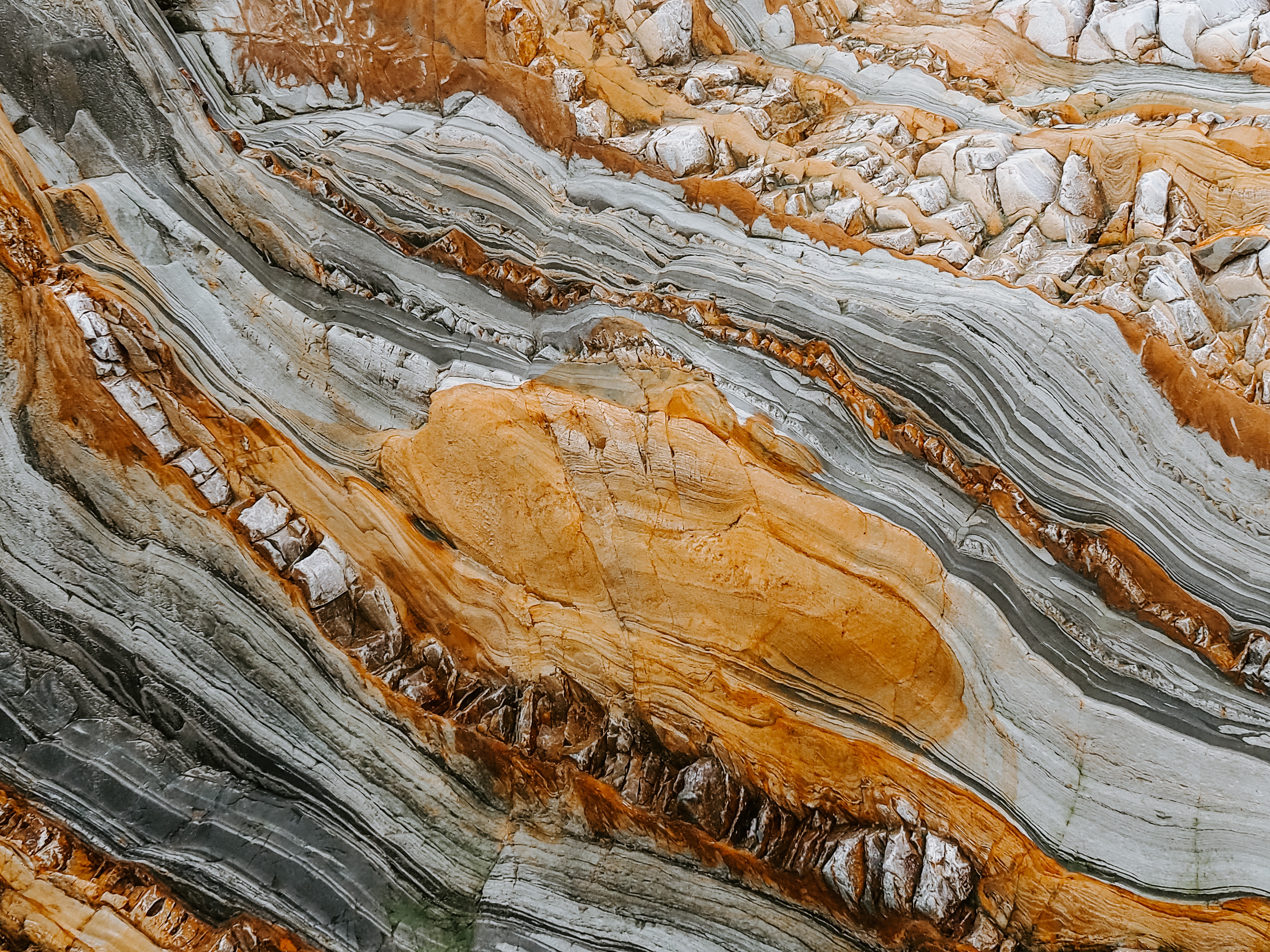 Close-up of layered rock formations with orange and gray strata HD Wallpaper
