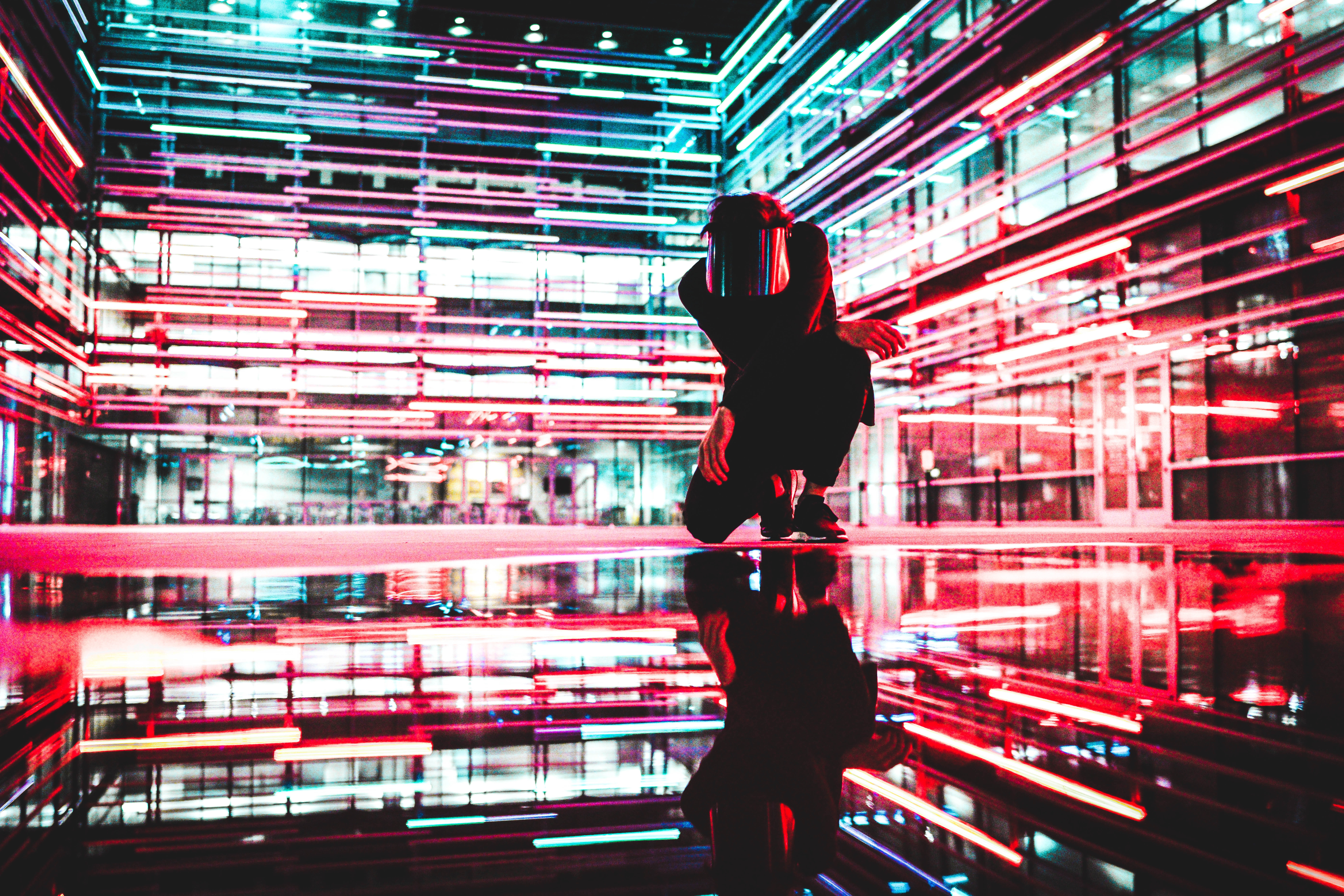 Person crouching in front of neon lights reflection HD Wallpaper