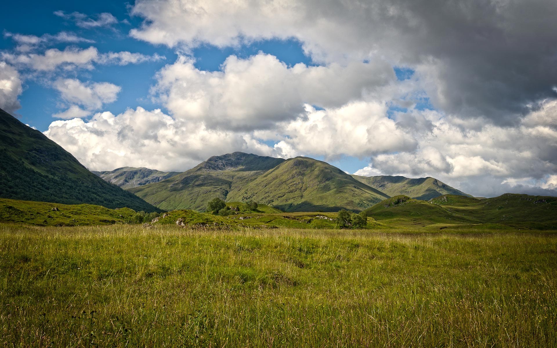Green mountains under a cloudy sky HD Wallpaper
