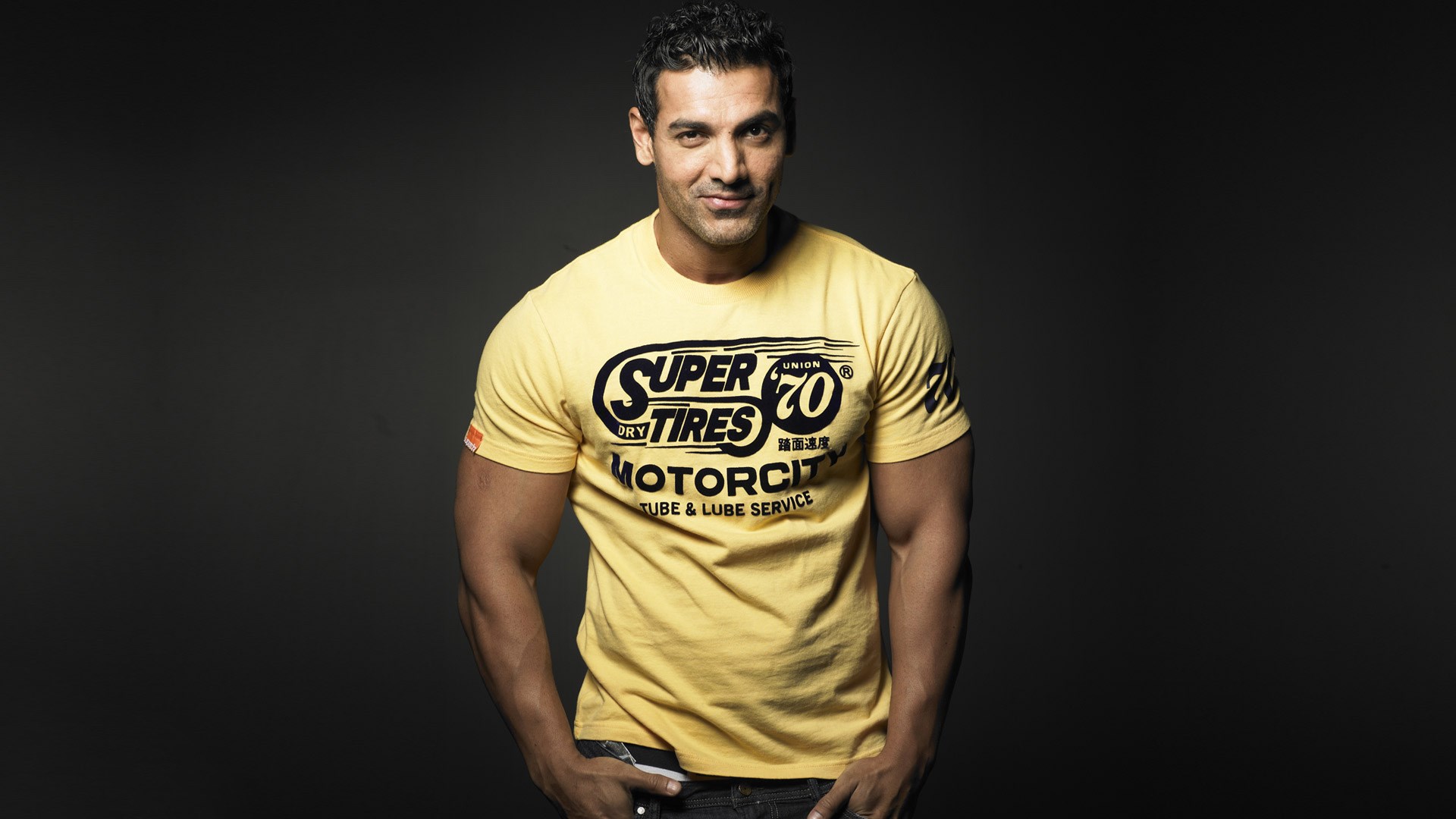 John Abraham in a yellow Super Dry Tires t-shirt HD Wallpaper