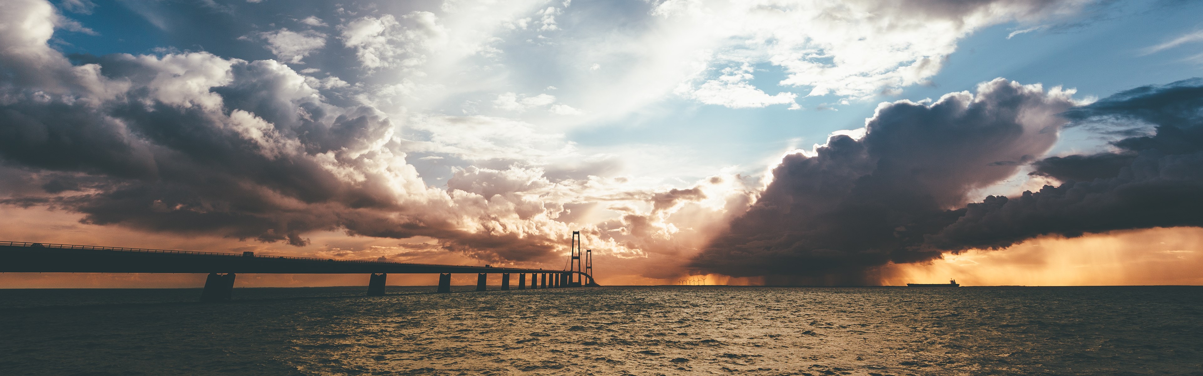 Bridge over water with dramatic clouds HD Wallpaper