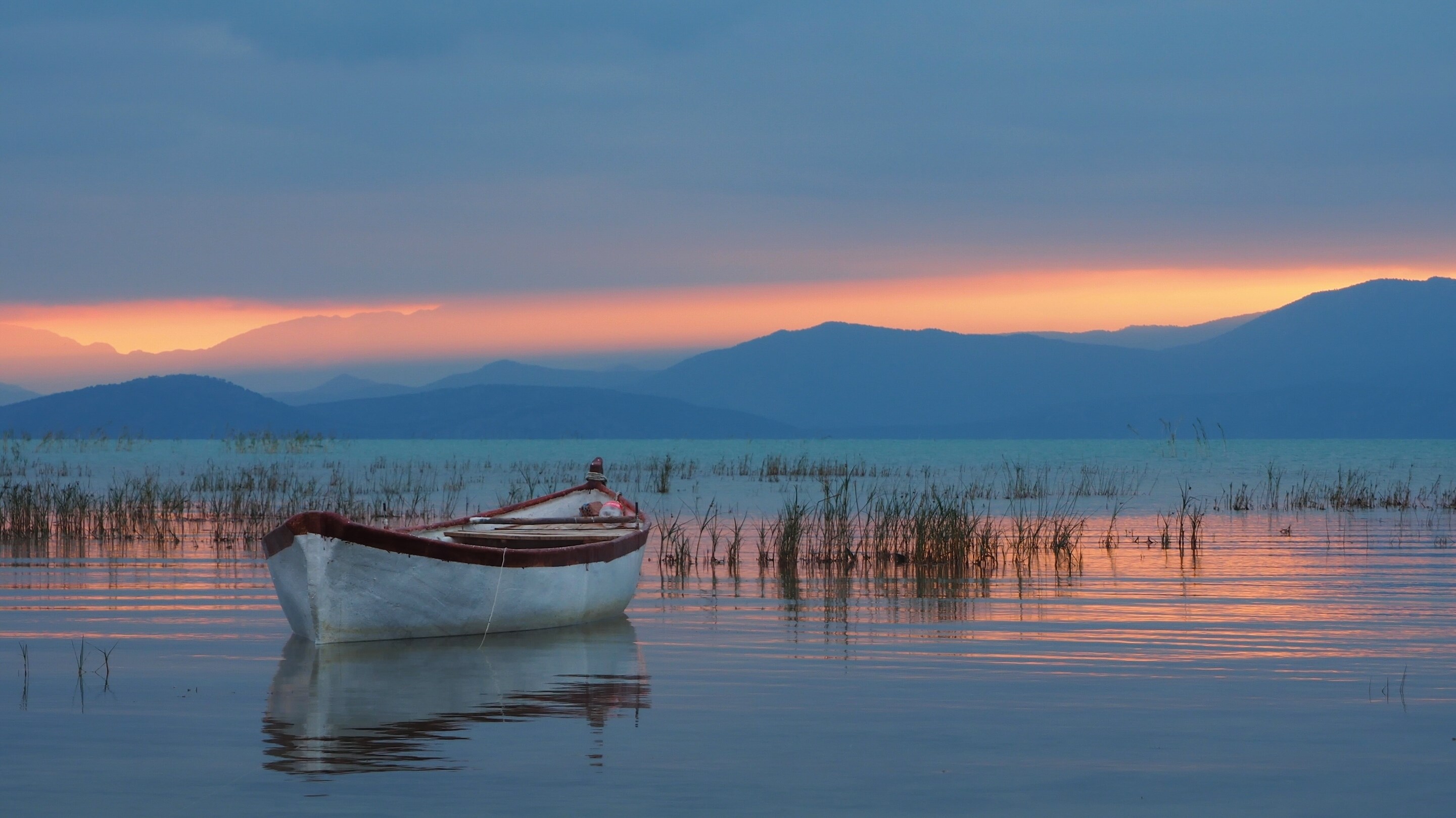 Boat on a lake at sunset with mountains HD Wallpaper