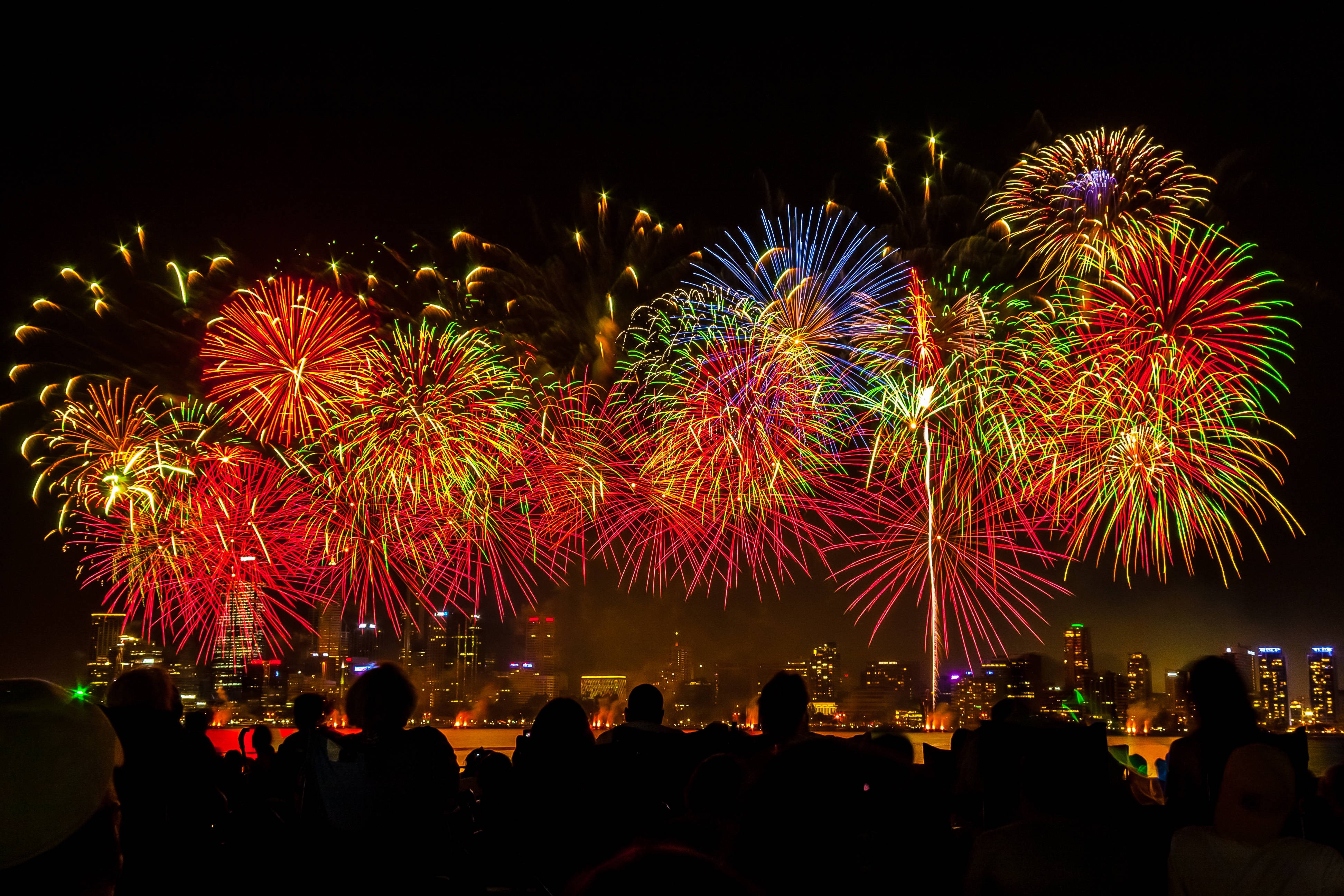 Fireworks display over a city skyline at night HD Wallpaper
