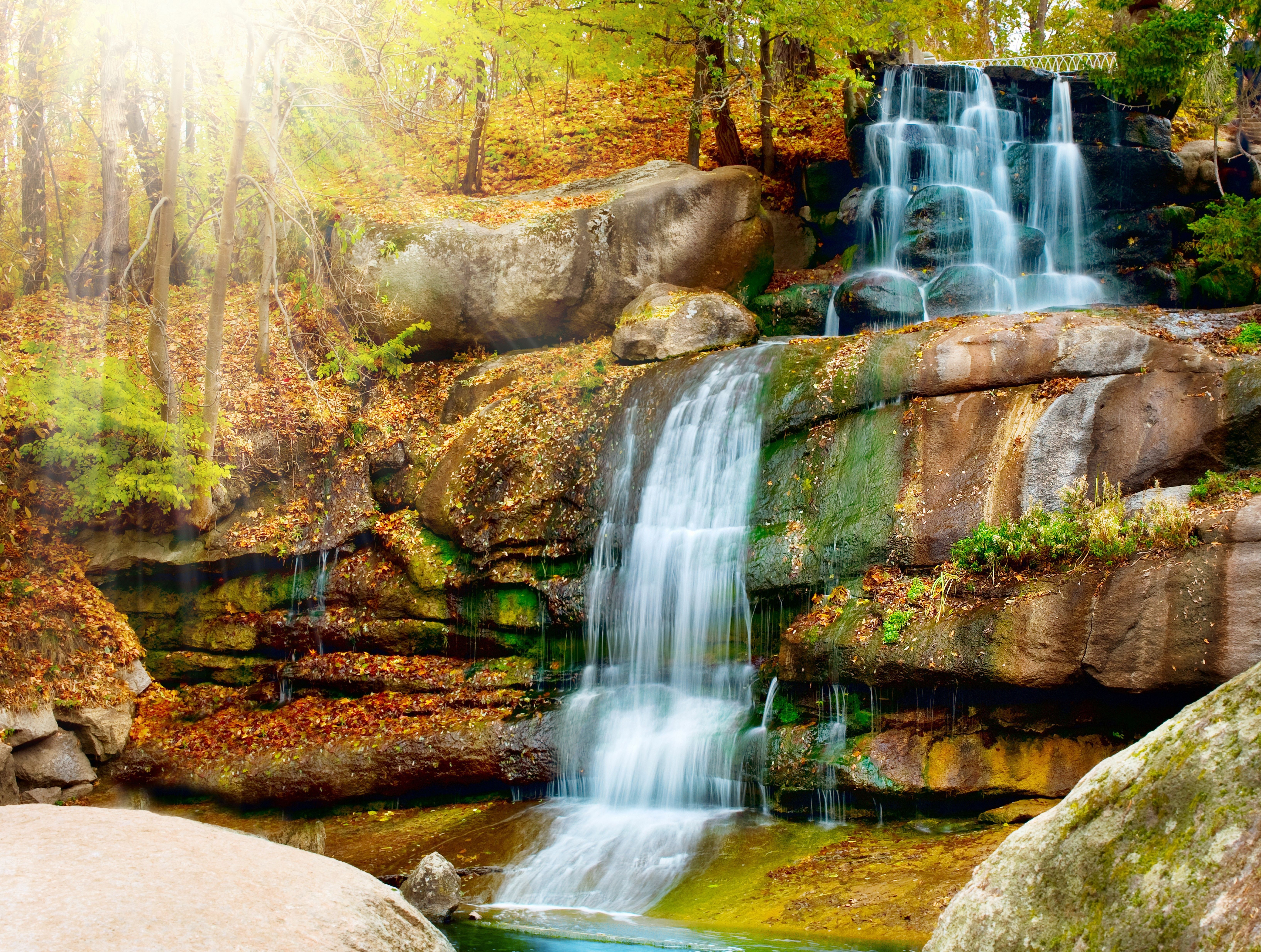 Waterfall in autumn forest with sun rays HD Wallpaper