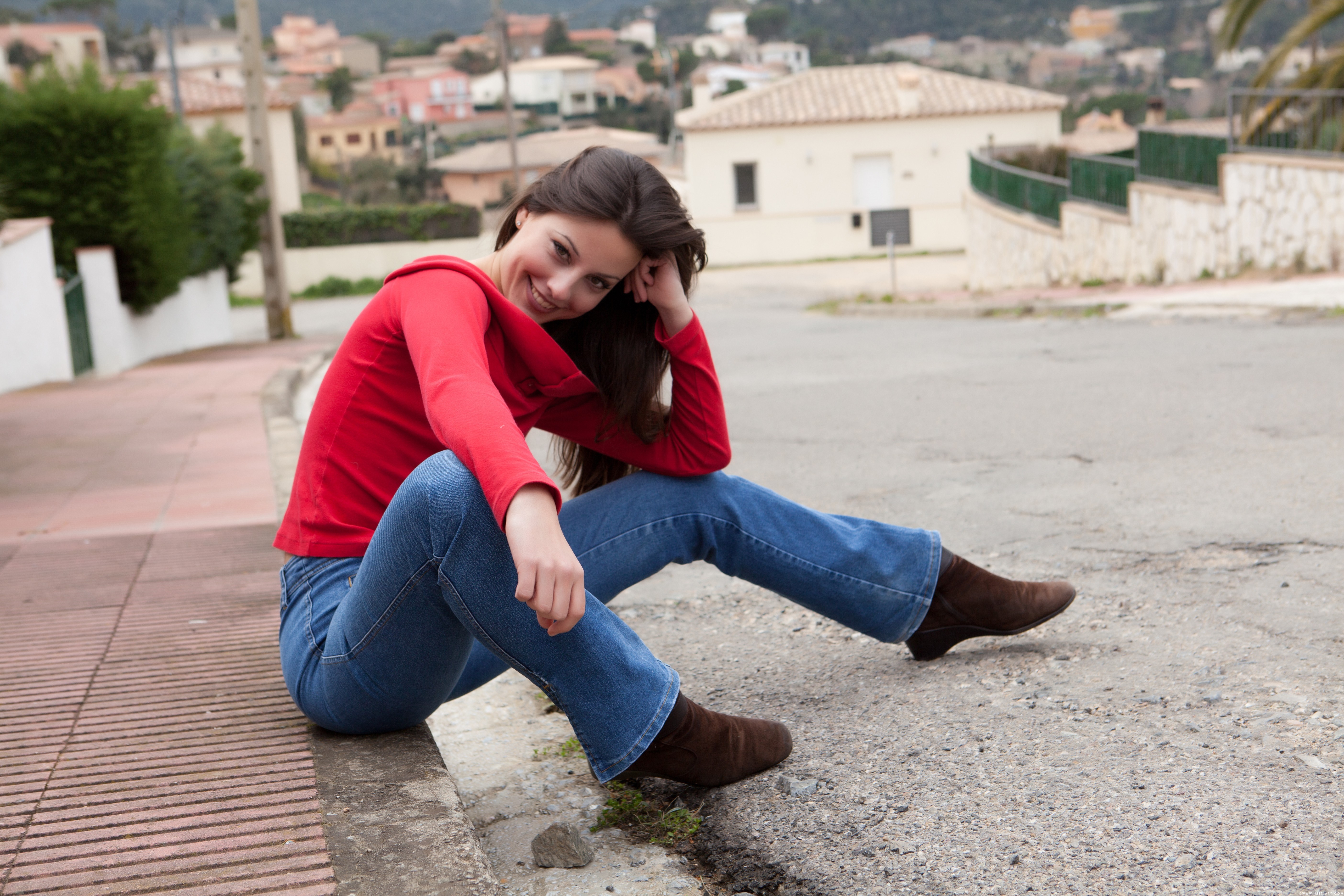 Smiling Woman Sitting on Roadside in Casual Outfit HD Wallpaper
