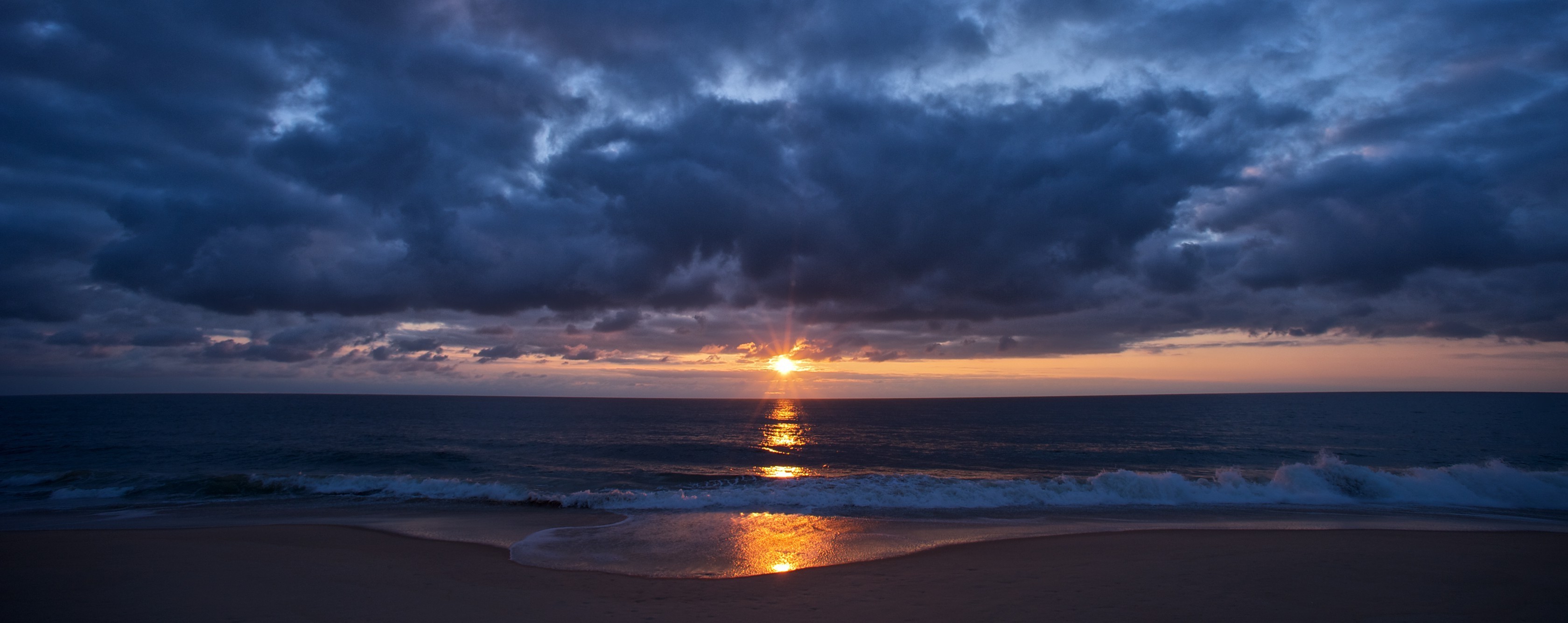 Sunset over the ocean with dark clouds and waves HD Wallpaper