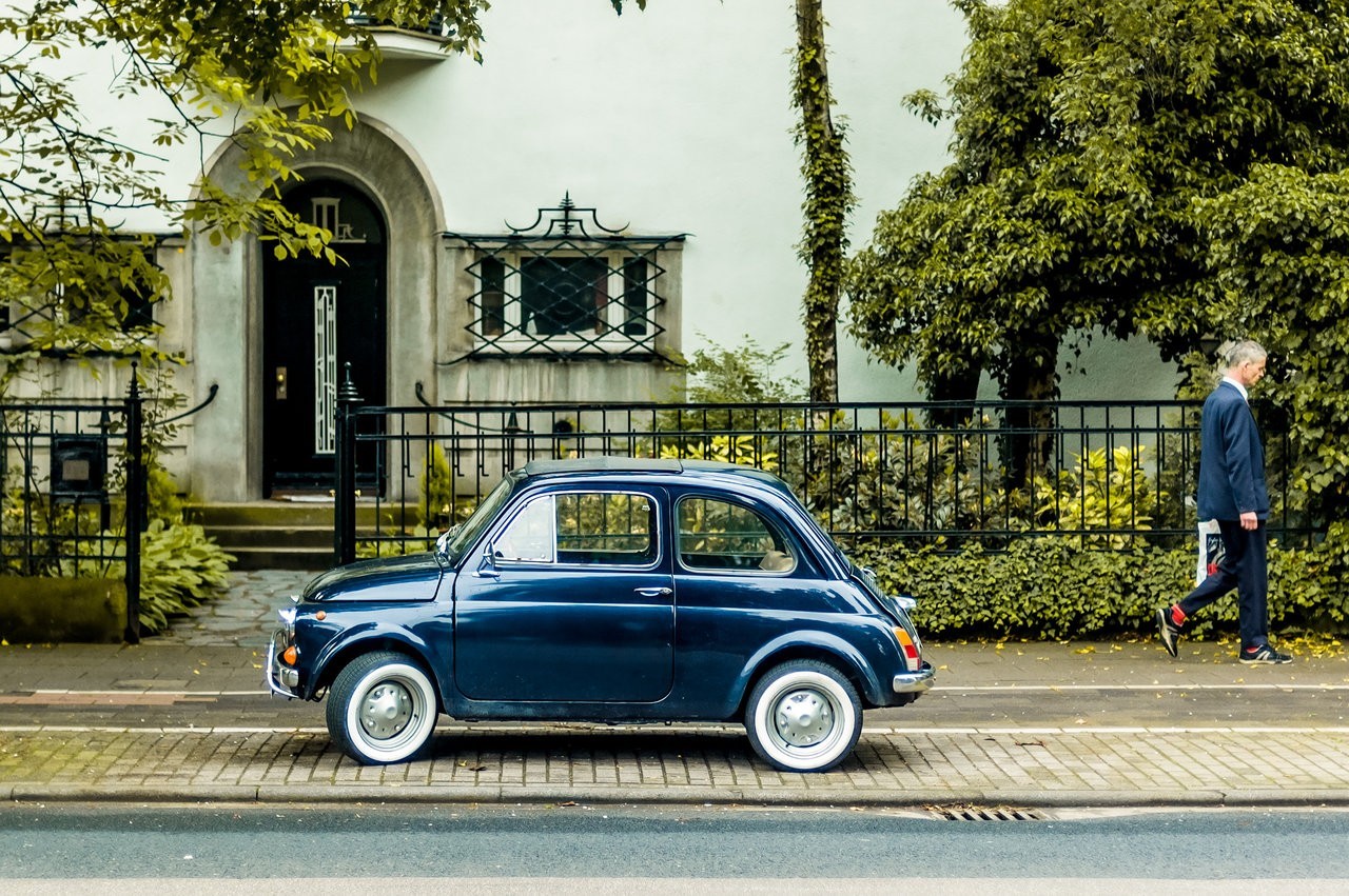 Blue Fiat 500 parked by a house with a man walking HD Wallpaper