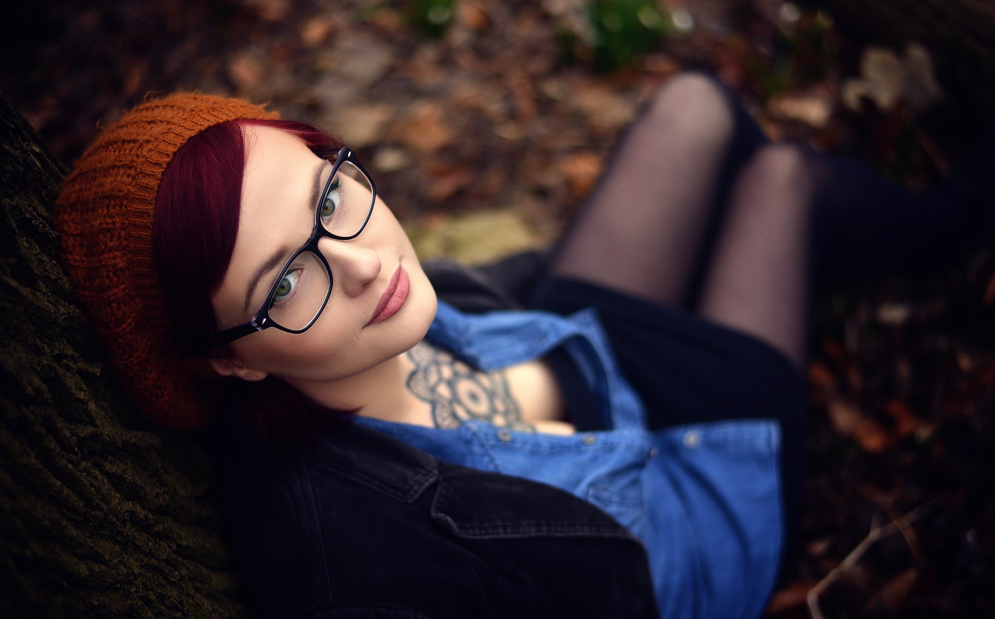 Woman with glasses and tattoos lying down outdoors HD Wallpaper