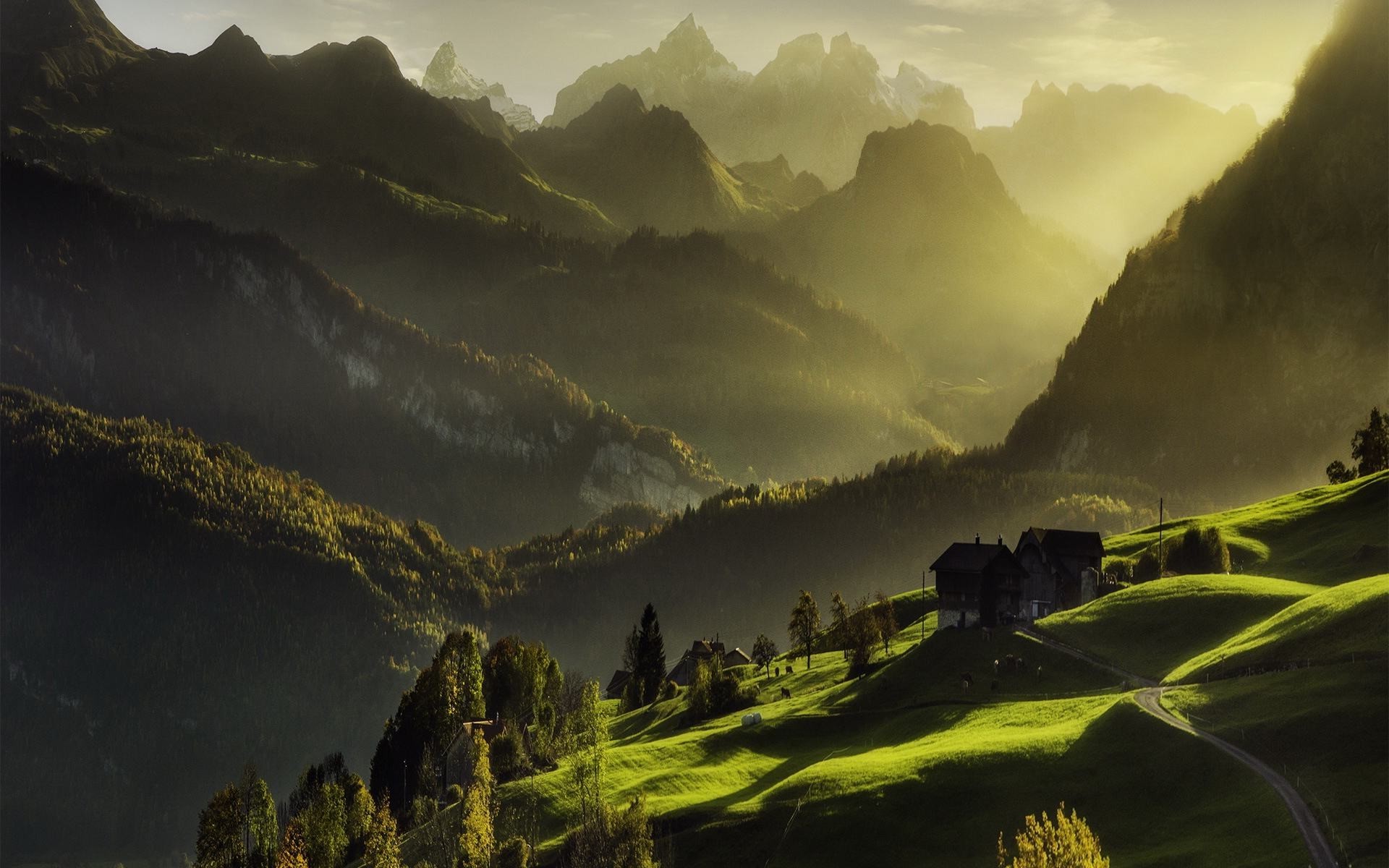 Sun rays over mountains and houses in a valley HD Wallpaper