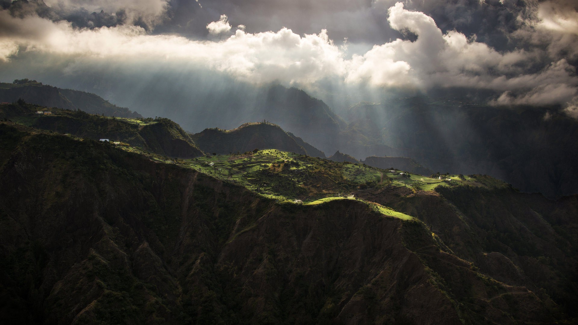 Sun rays breaking through clouds over mountainous landscape HD Wallpaper