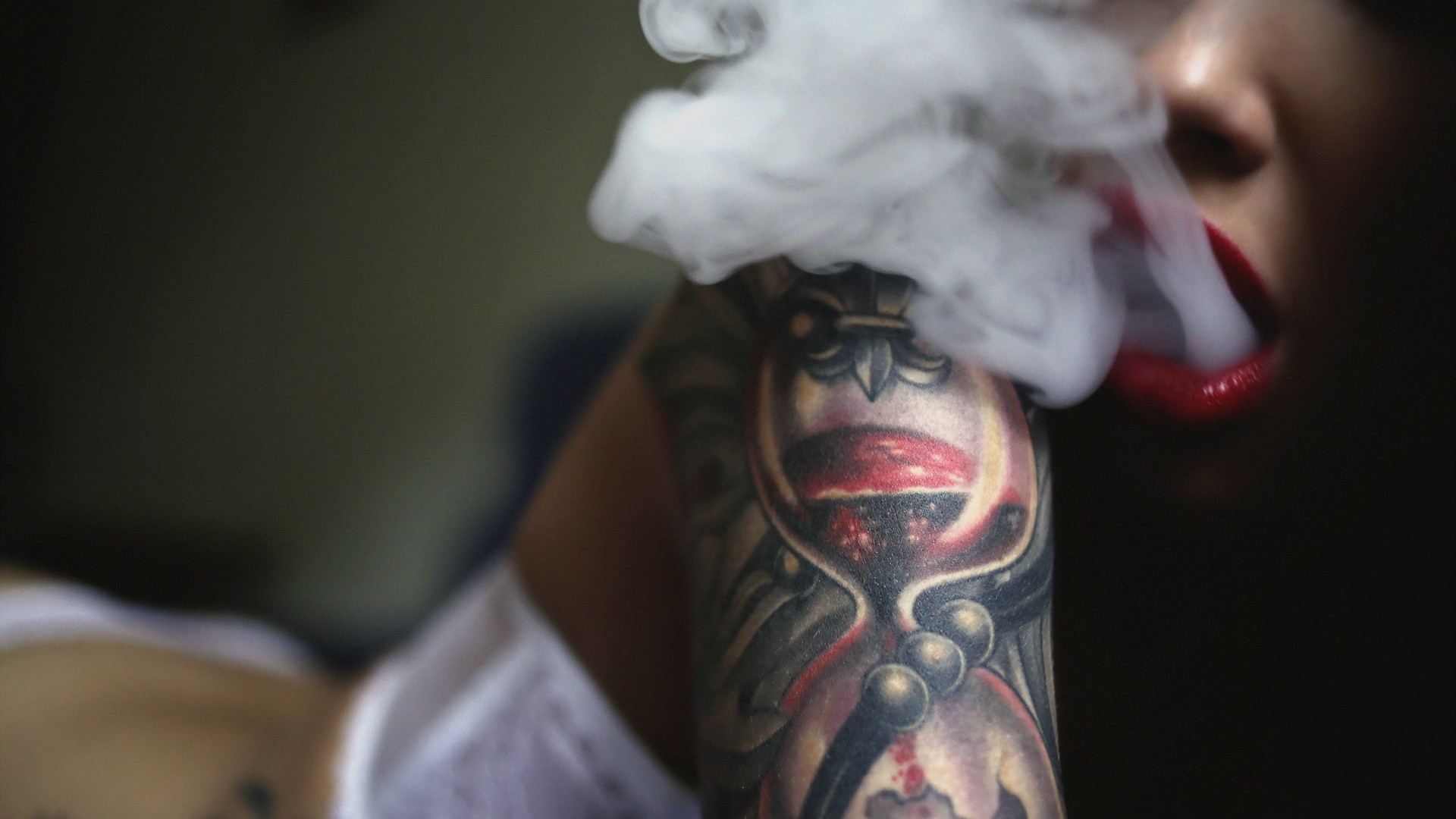Woman with hourglass tattoo exhales smoke HD Wallpaper
