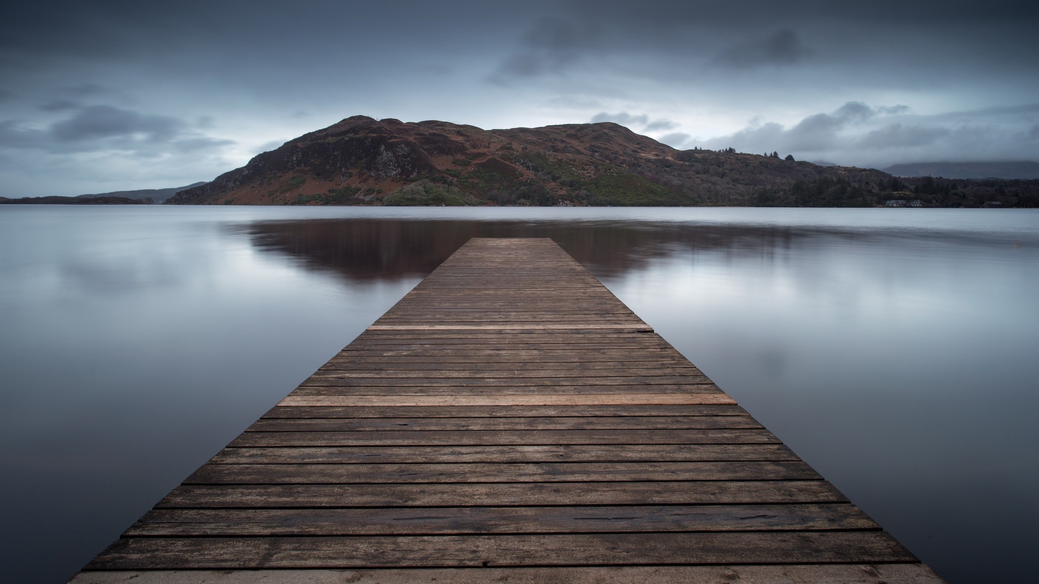 Wooden pier on a calm lake with mountains in the background HD Wallpaper