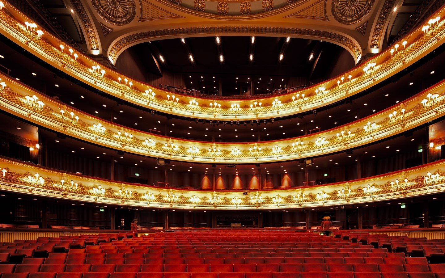 Grand opera house interior with red seats and ornate balconies HD Wallpaper