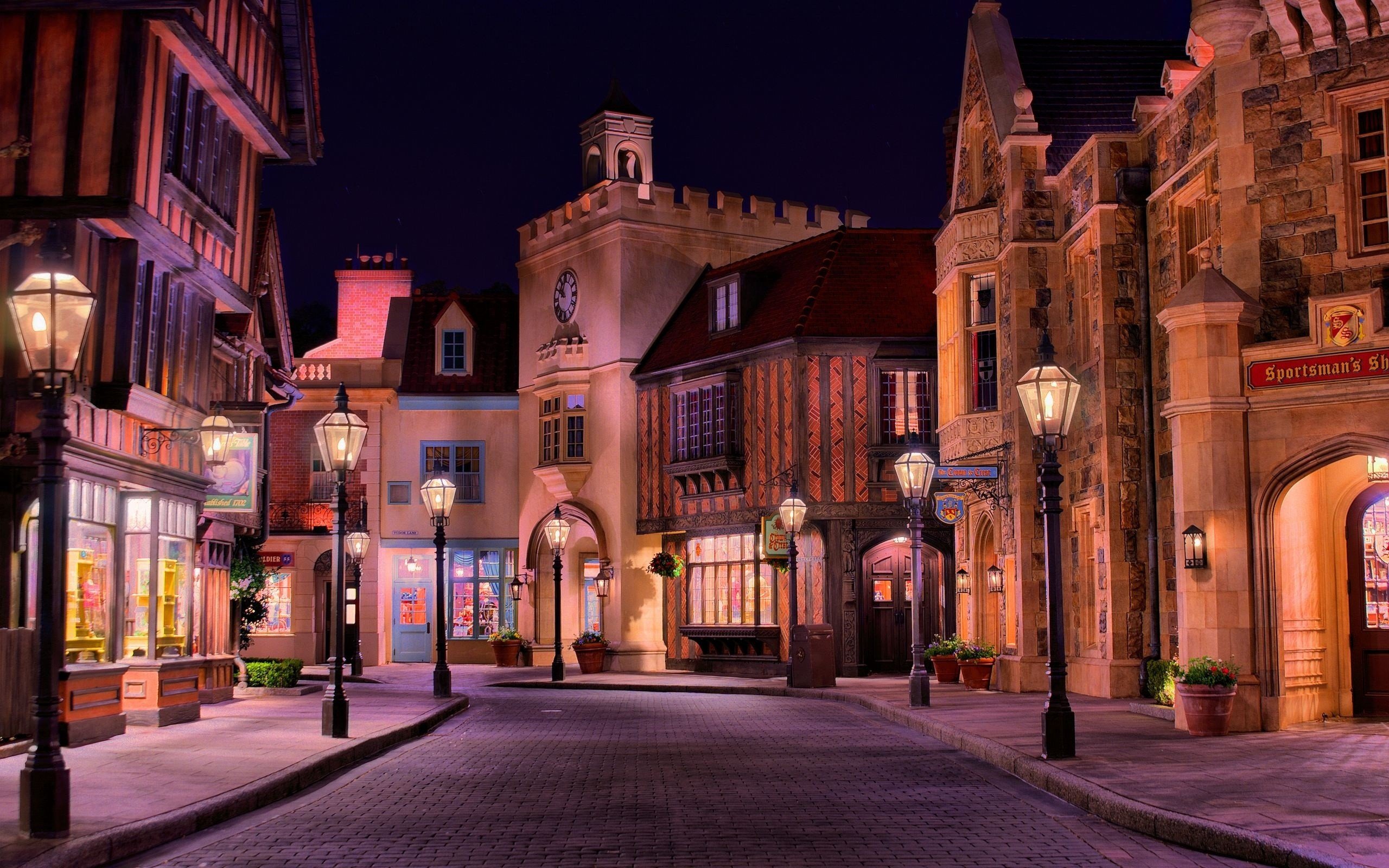 European street at night with lampposts and shops HD Wallpaper