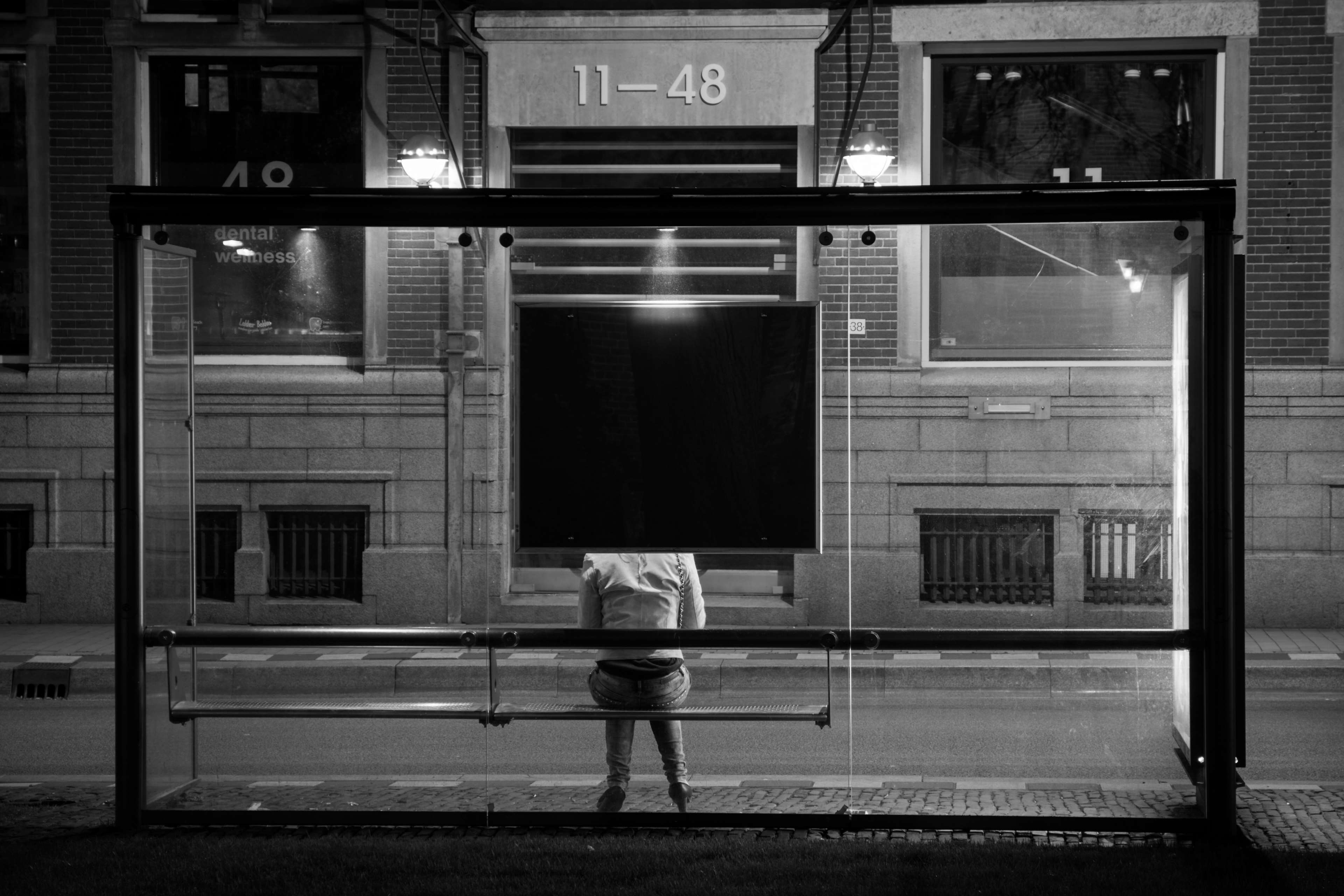 Woman sitting at a bus stop at night HD Wallpaper