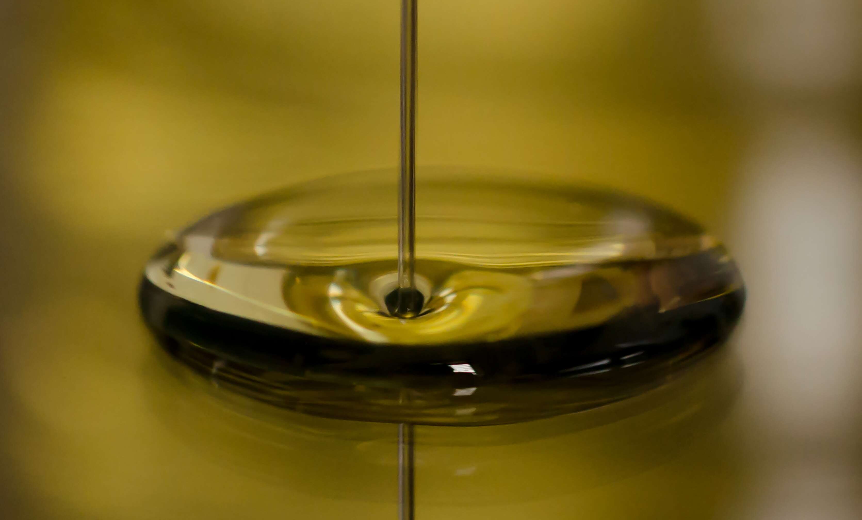 A thin stream of oil falling into a pool of oil HD Wallpaper