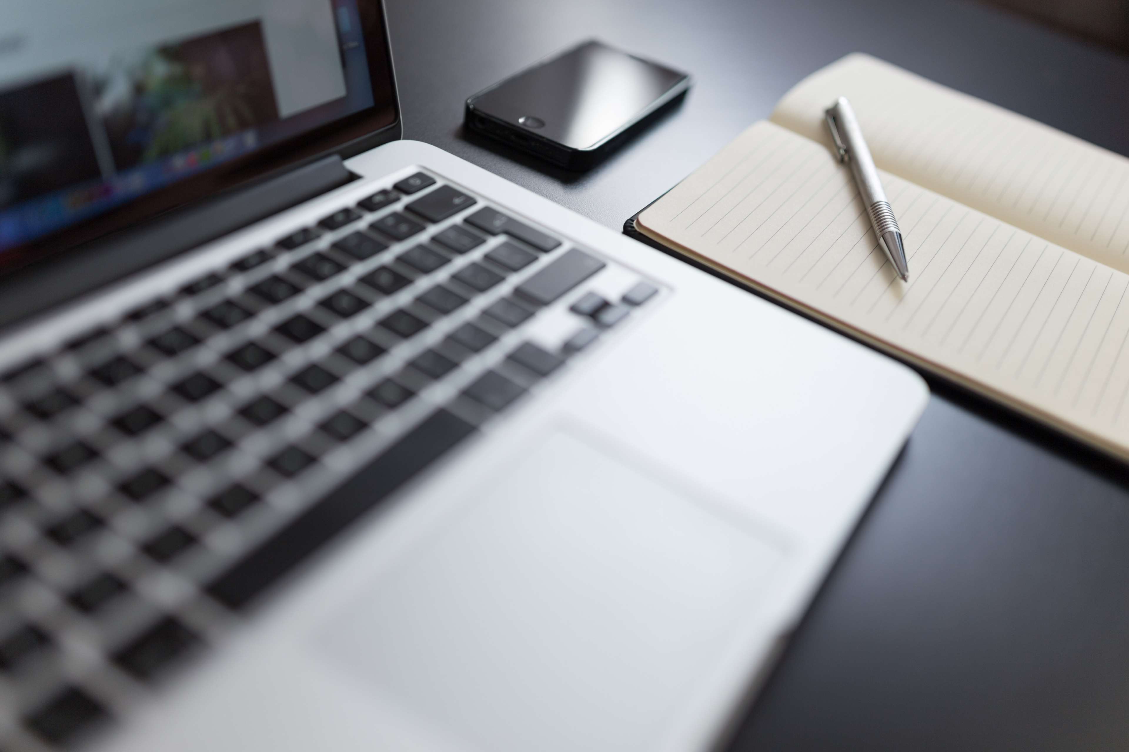MacBook, smartphone, notebook, and pen on a desk 4K HD Wallpaper
