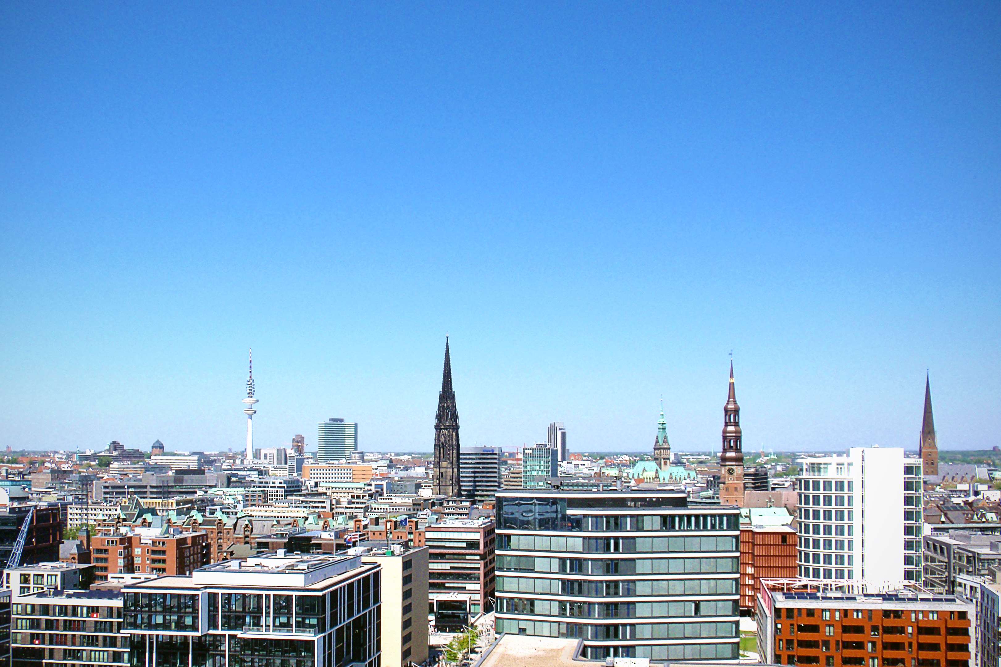 Hamburg skyline with modern and historic buildings under blue sky HD Wallpaper