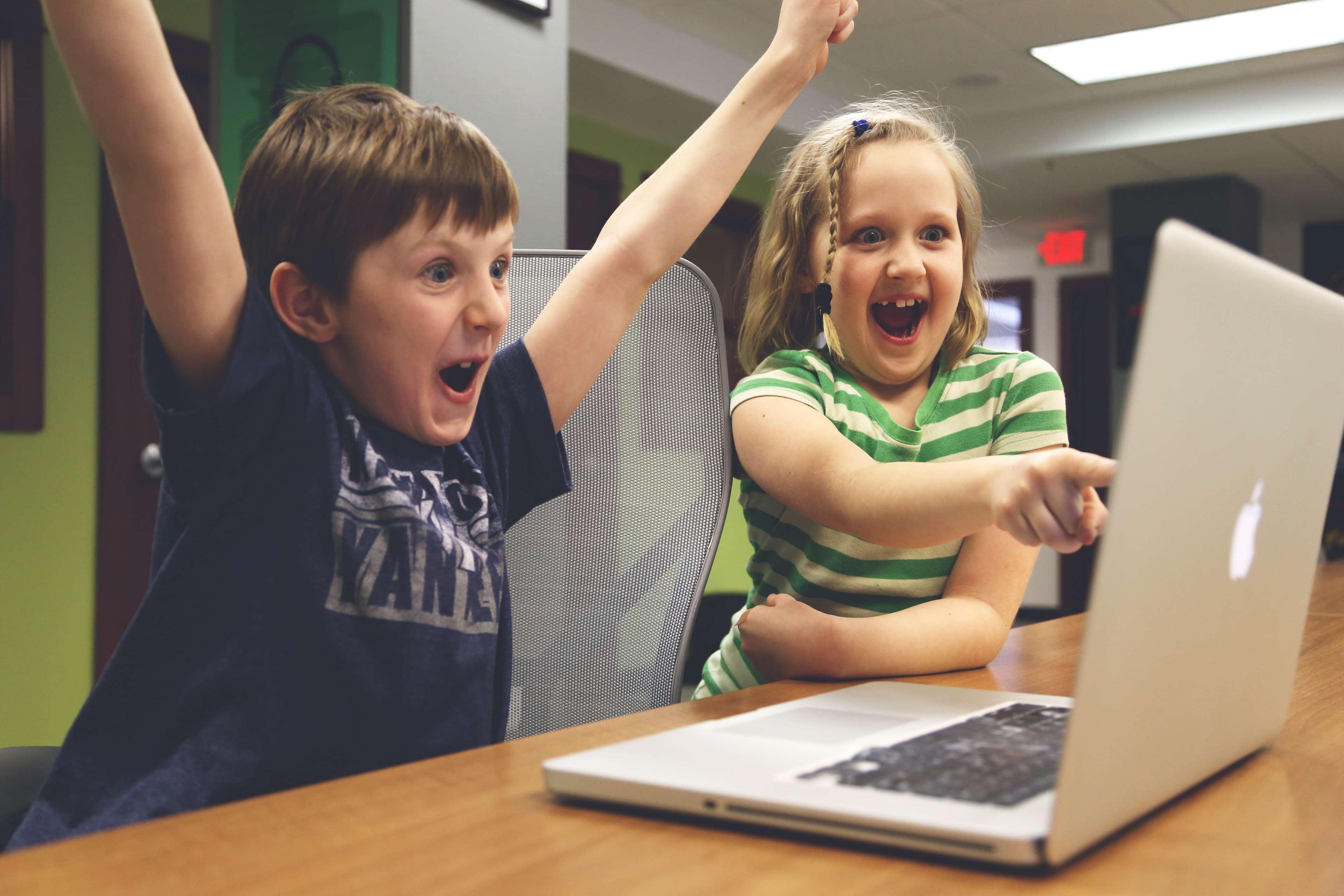 Excited children looking at a MacBook 4K HD Wallpaper