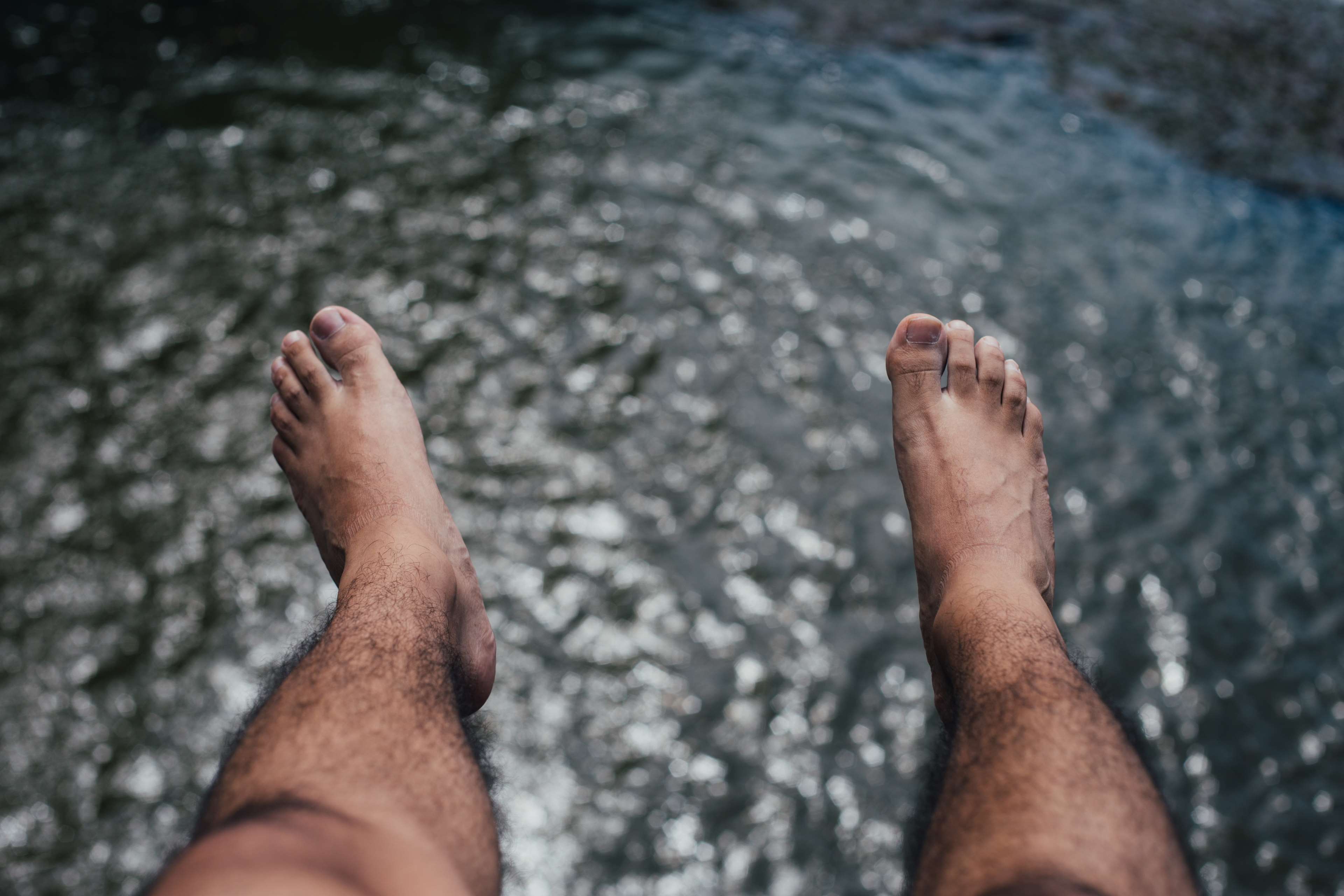 Male hairy legs and feet over water HD Wallpaper