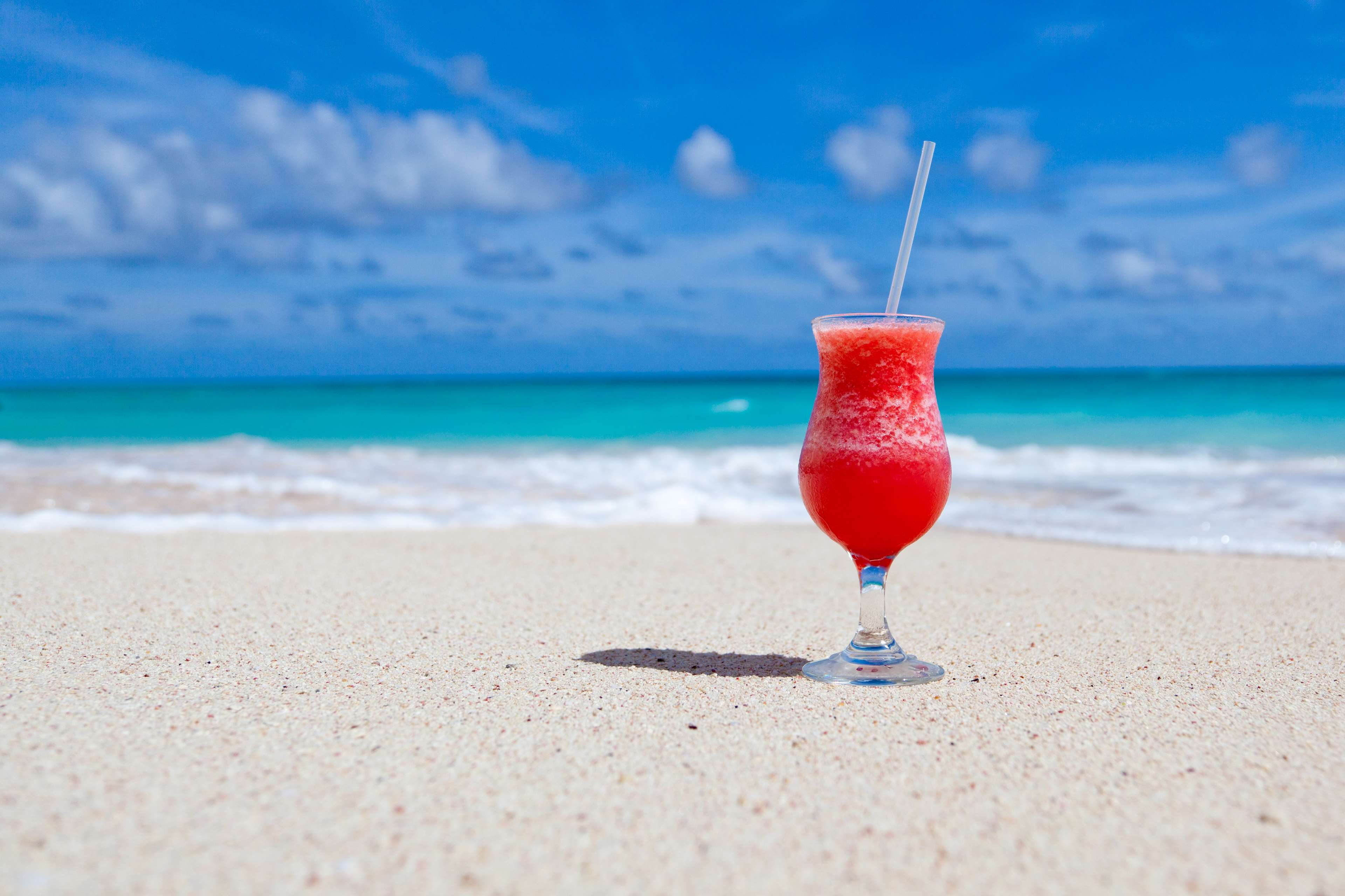 Red cocktail on a sandy beach with ocean background HD Wallpaper