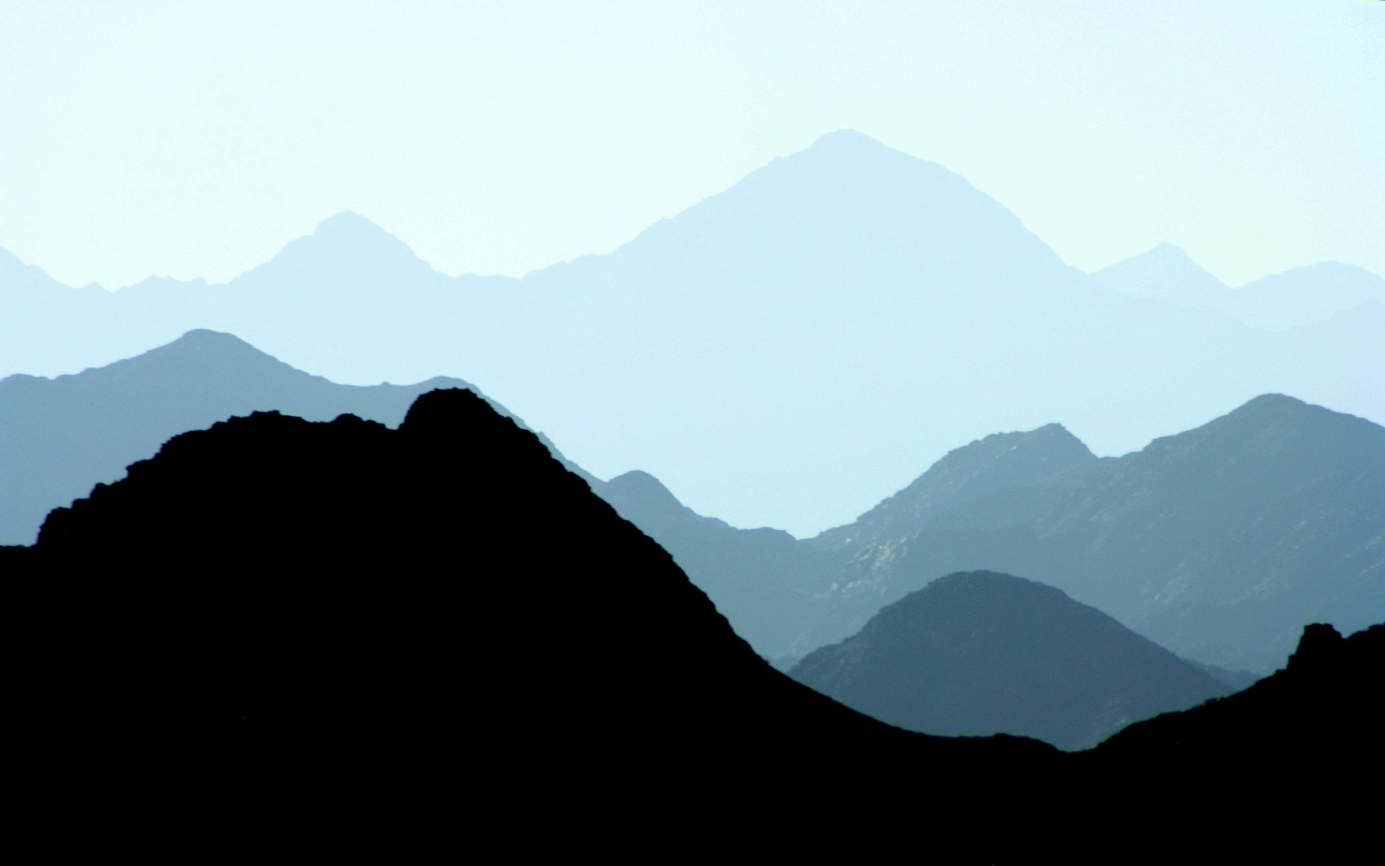 Silhouette of mountain ranges against a hazy sky HD Wallpaper