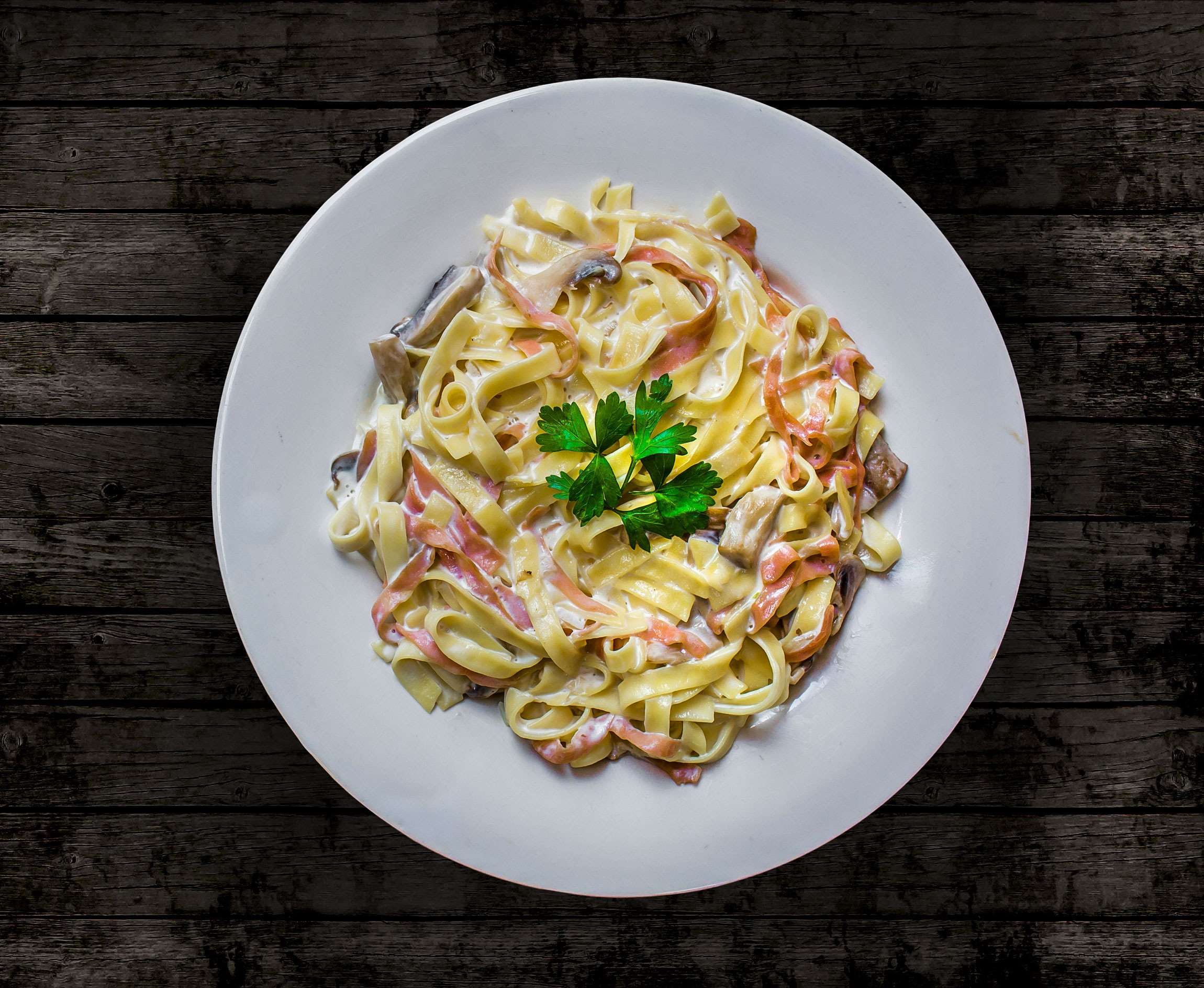 Tagliatelle pasta with ham and mushrooms on a white plate HD Wallpaper