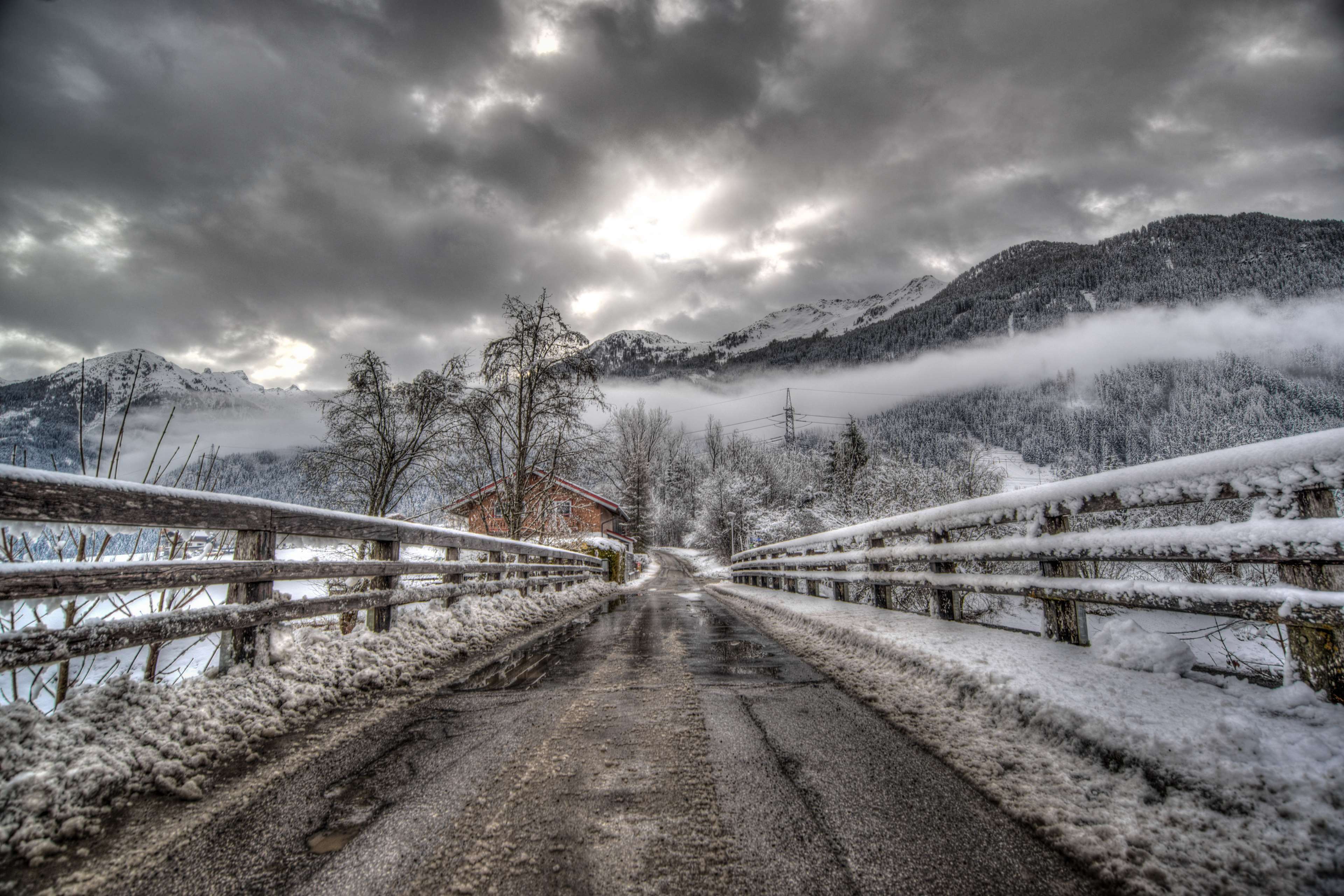 Snowy bridge over a road with mountains and clouds HD Wallpaper