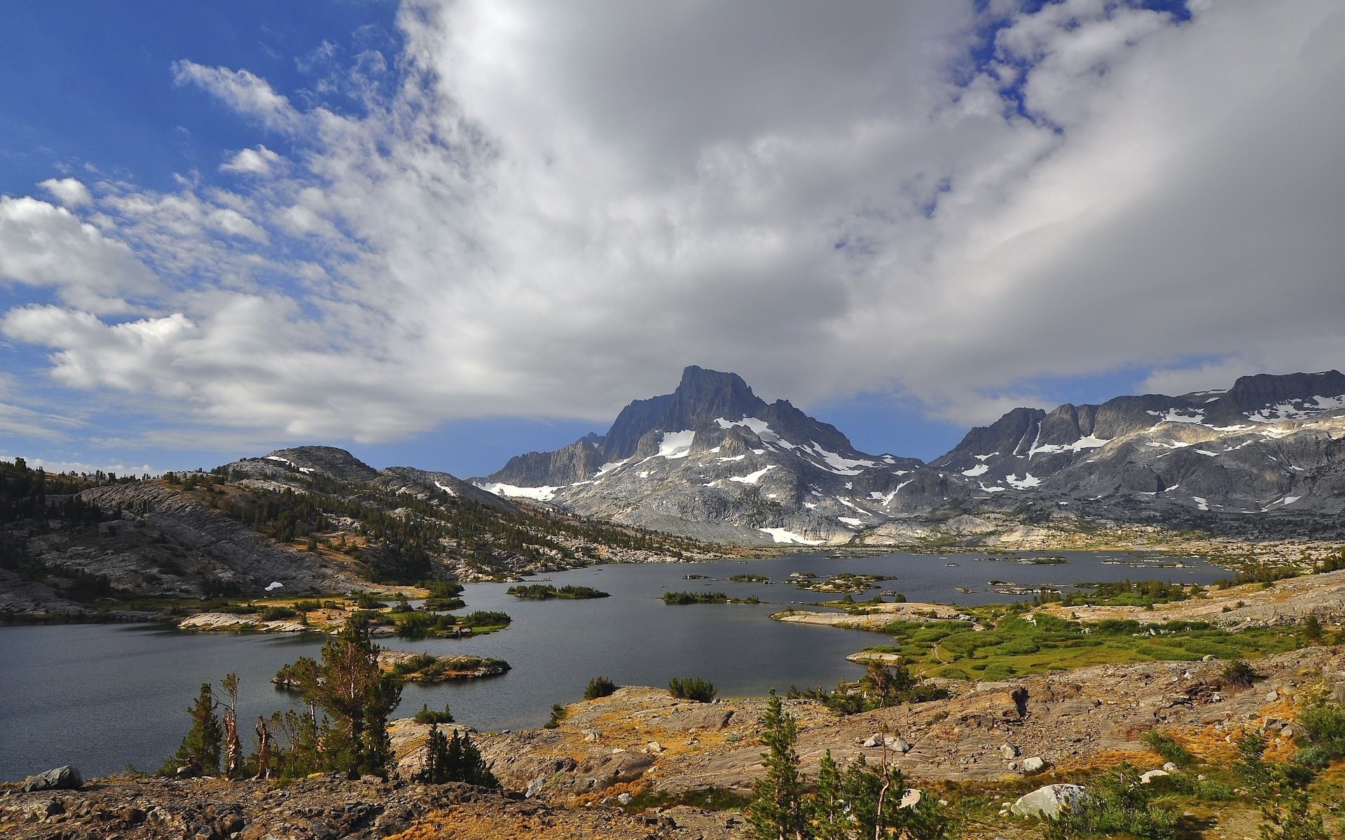 Mountain lake with rocky shores and snow-capped peaks HD Wallpaper