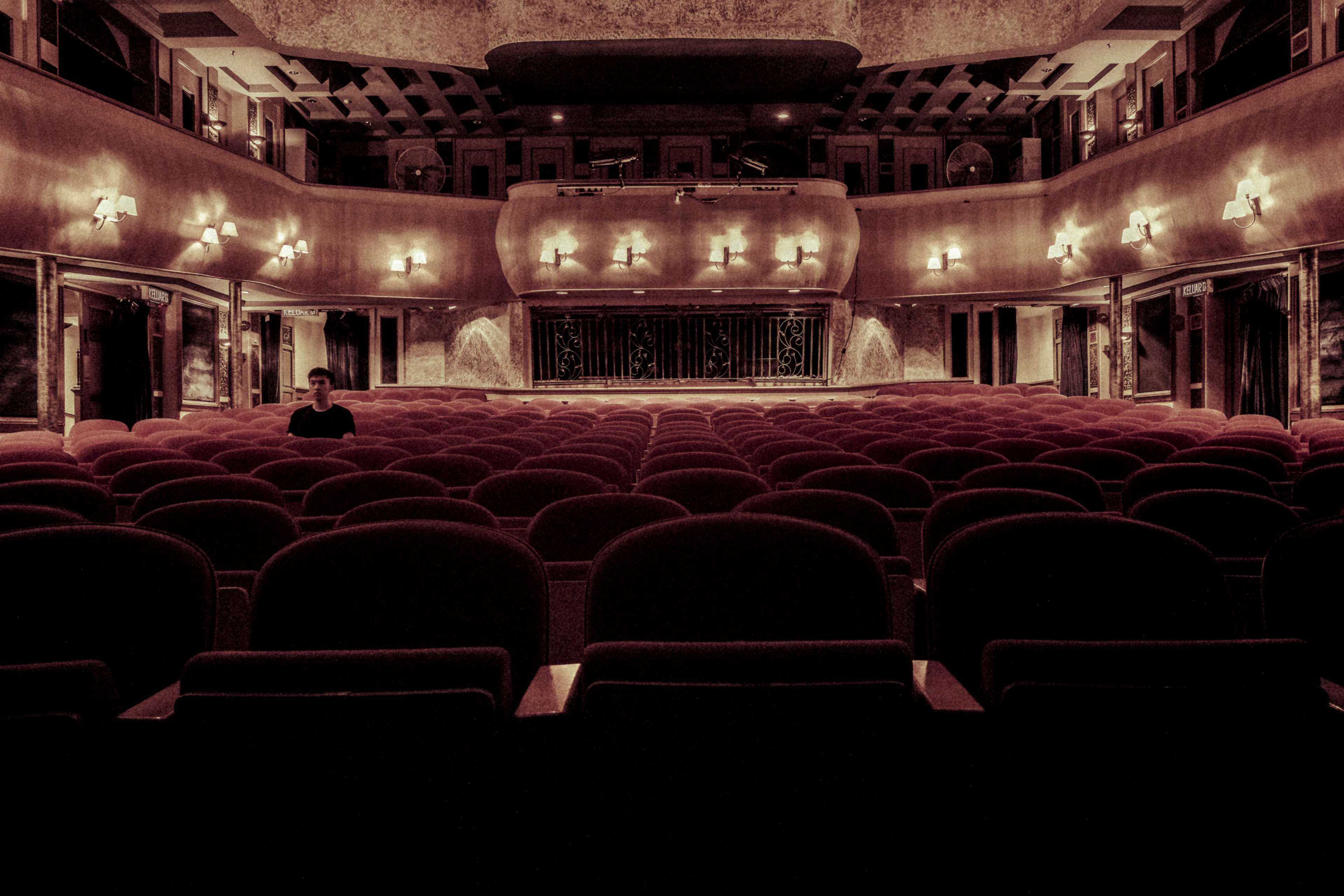 Man sitting alone in an empty theater auditorium HD Wallpaper