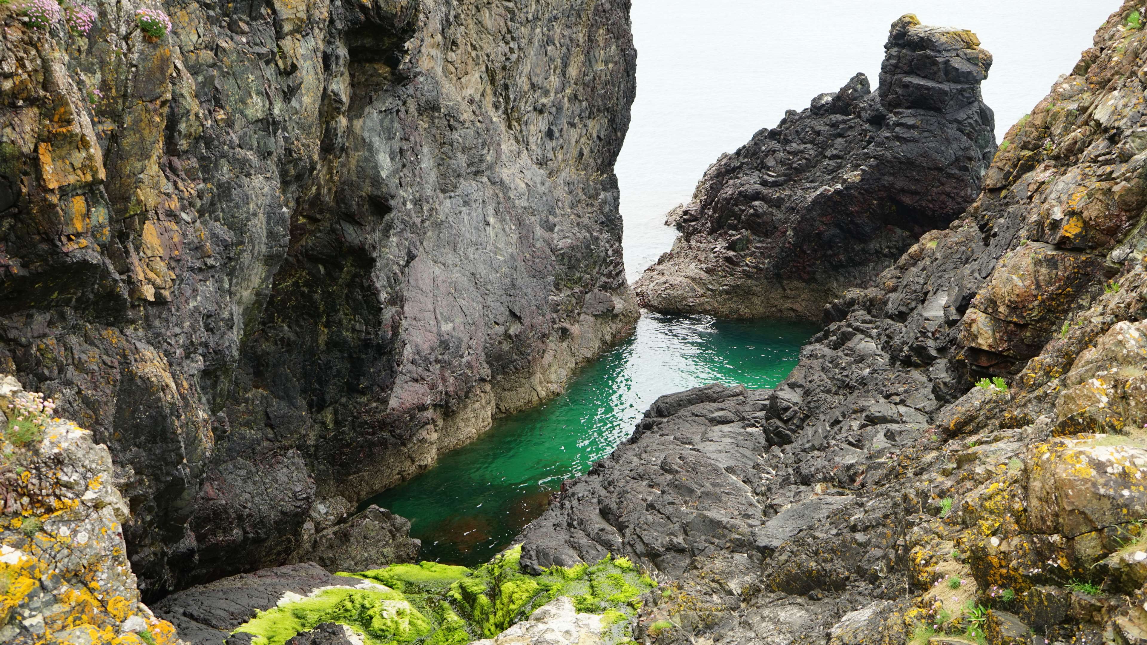 Rocky coast with emerald green water HD Wallpaper