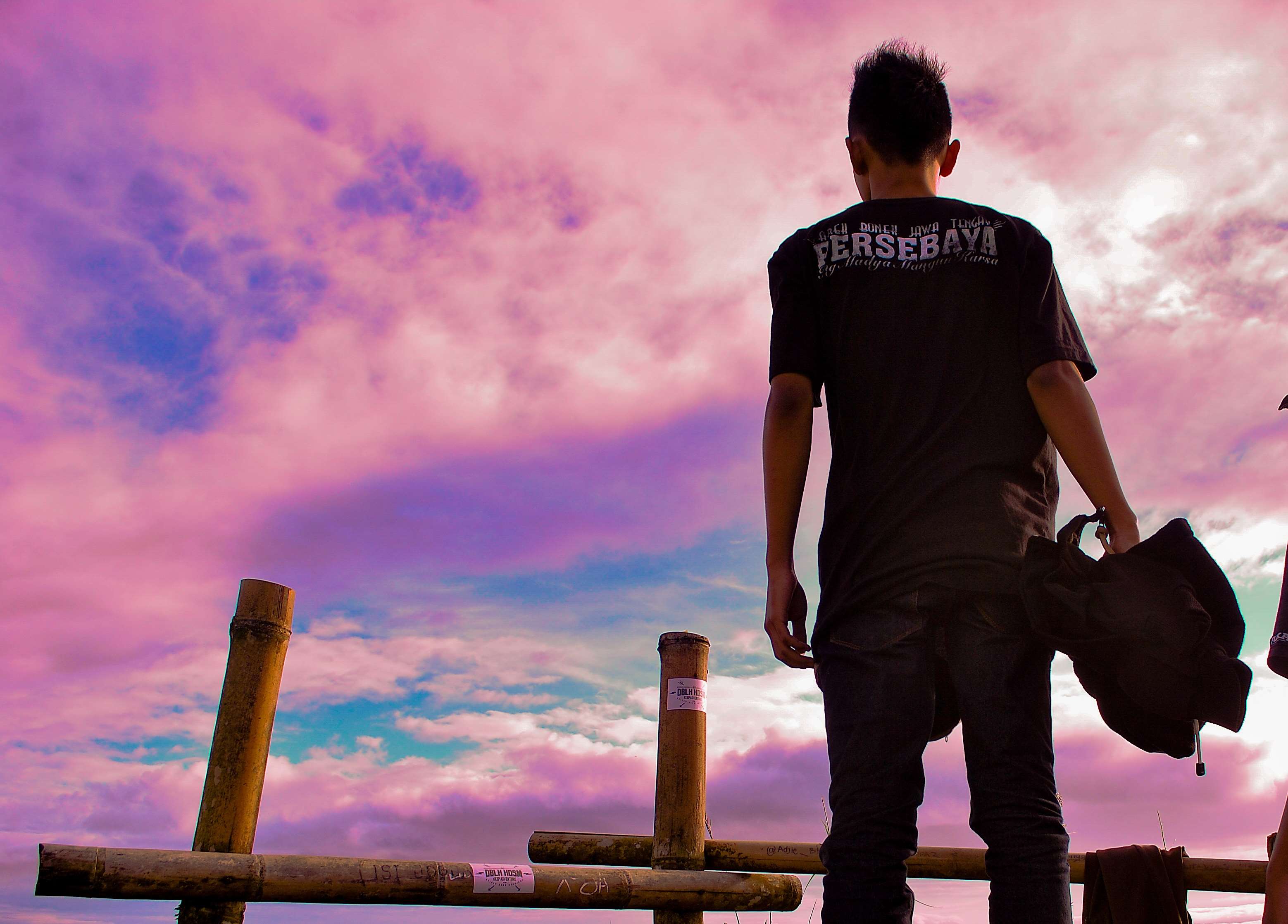 Man standing by bamboo fence at sunset HD Wallpaper