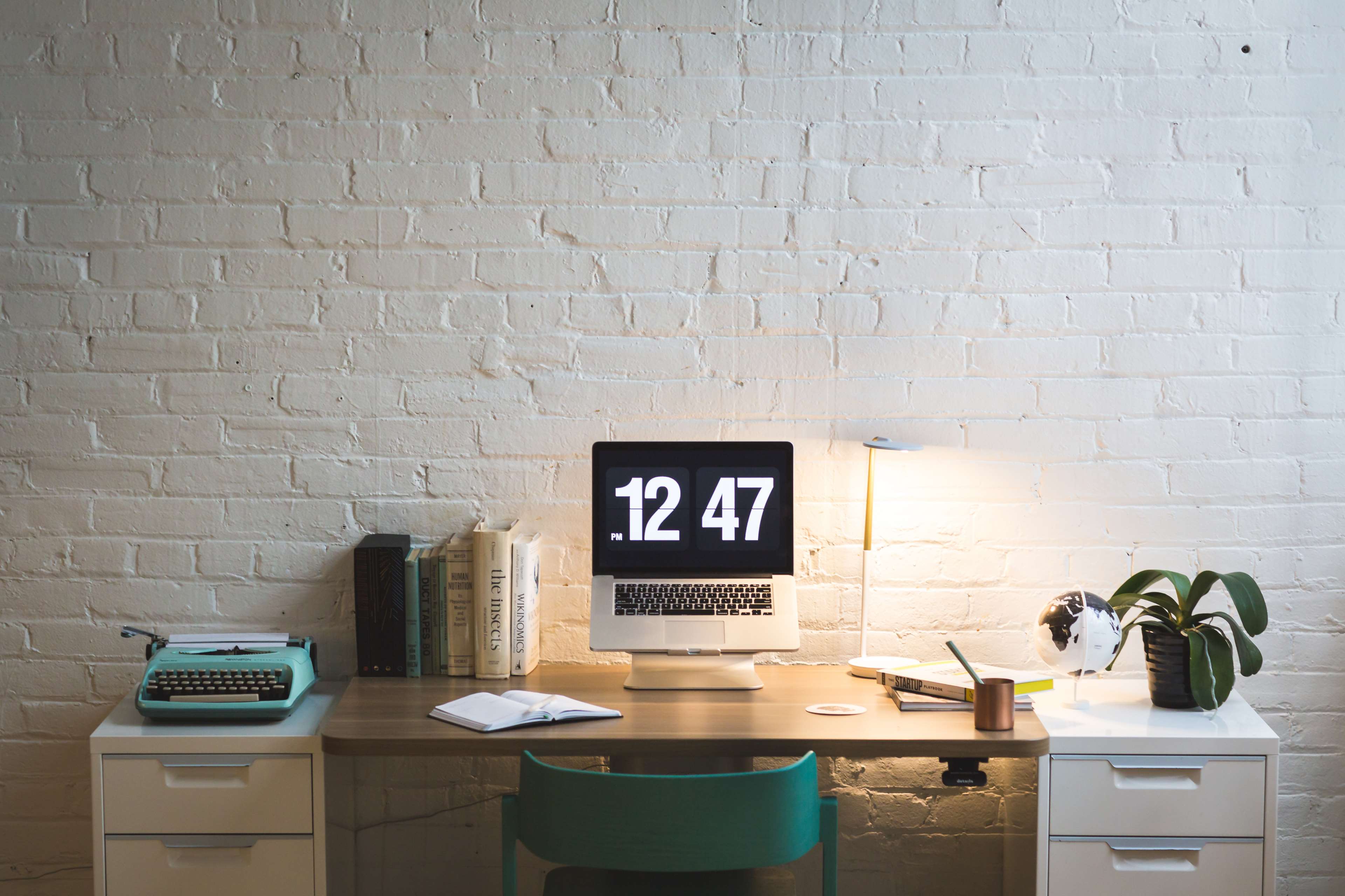Desk with laptop, typewriter, books, and plant HD Wallpaper