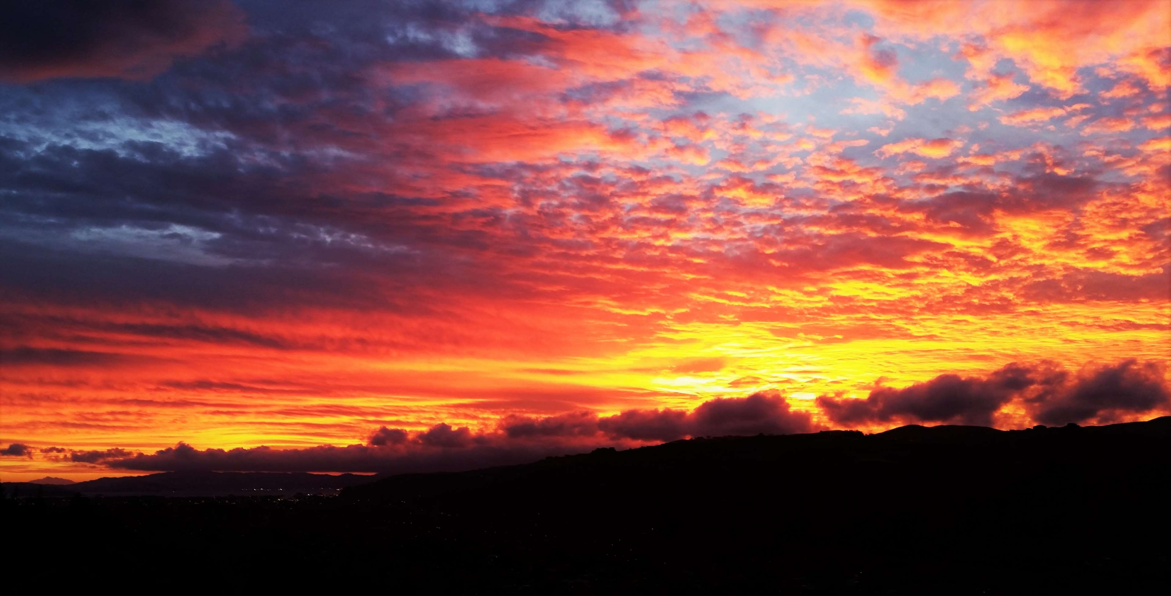 Dramatic sunset sky with silhouette of land HD Wallpaper