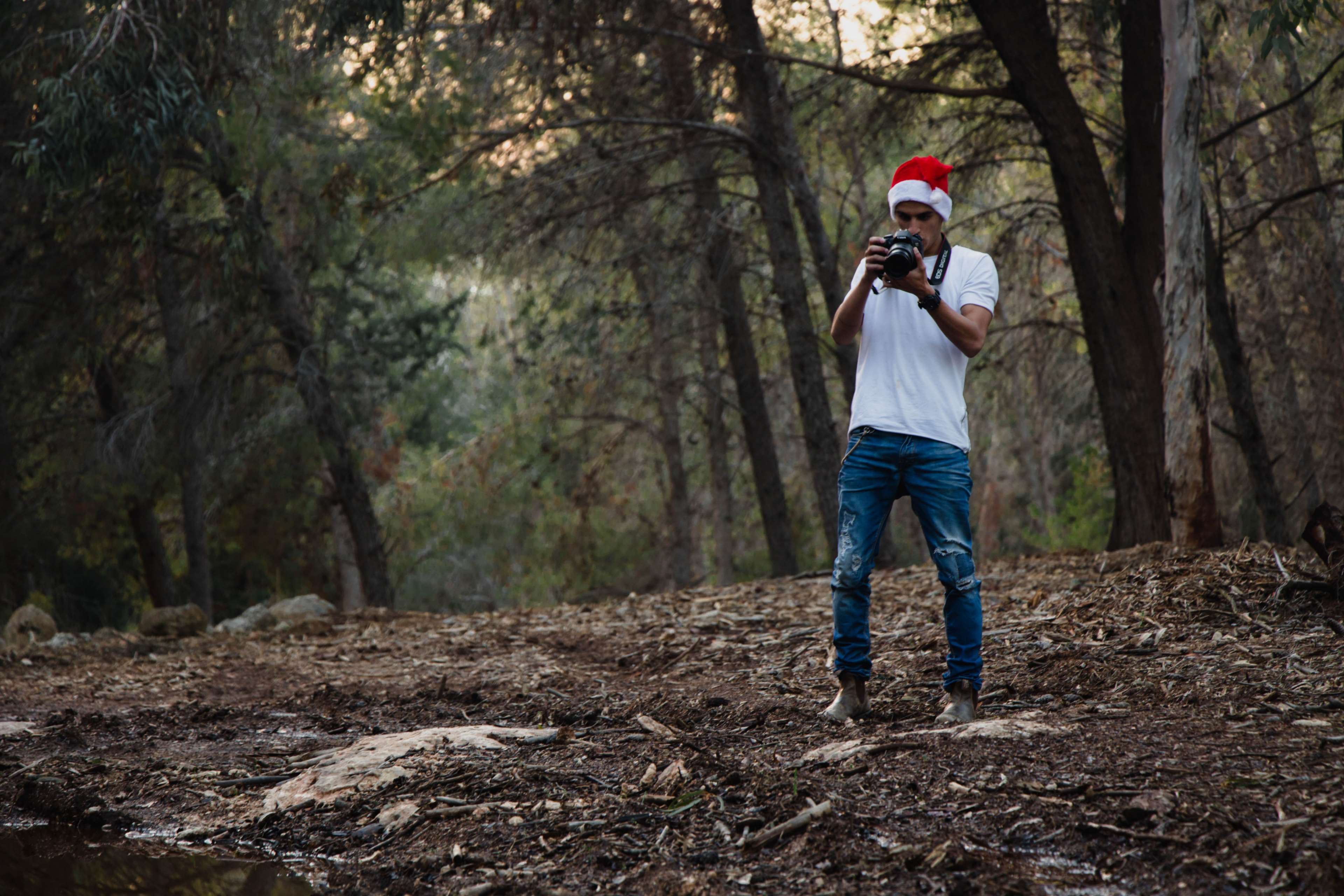 Man in Santa hat taking photos in forest HD Wallpaper
