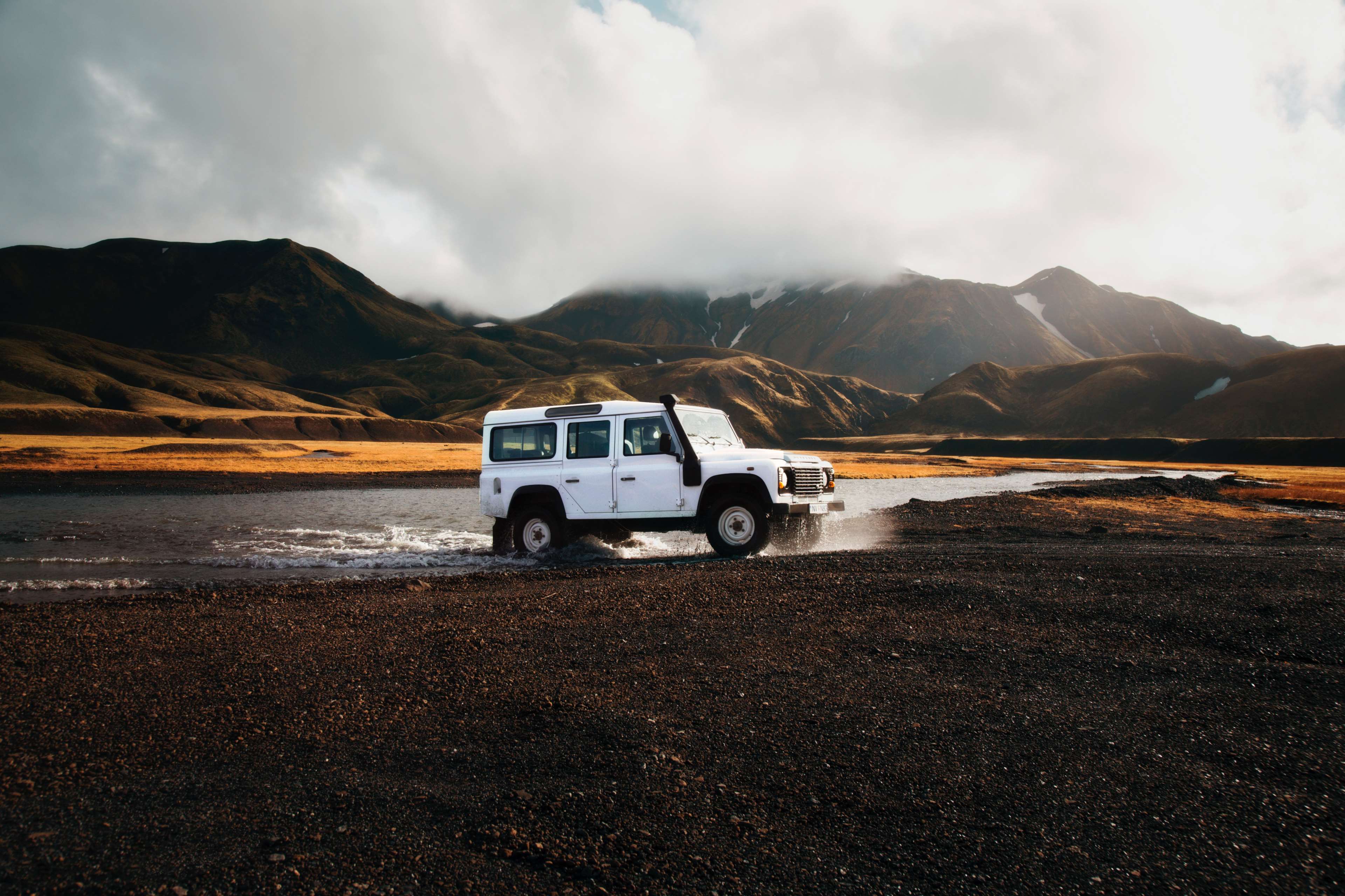 White Land Rover Defender driving through a river in Iceland HD Wallpaper