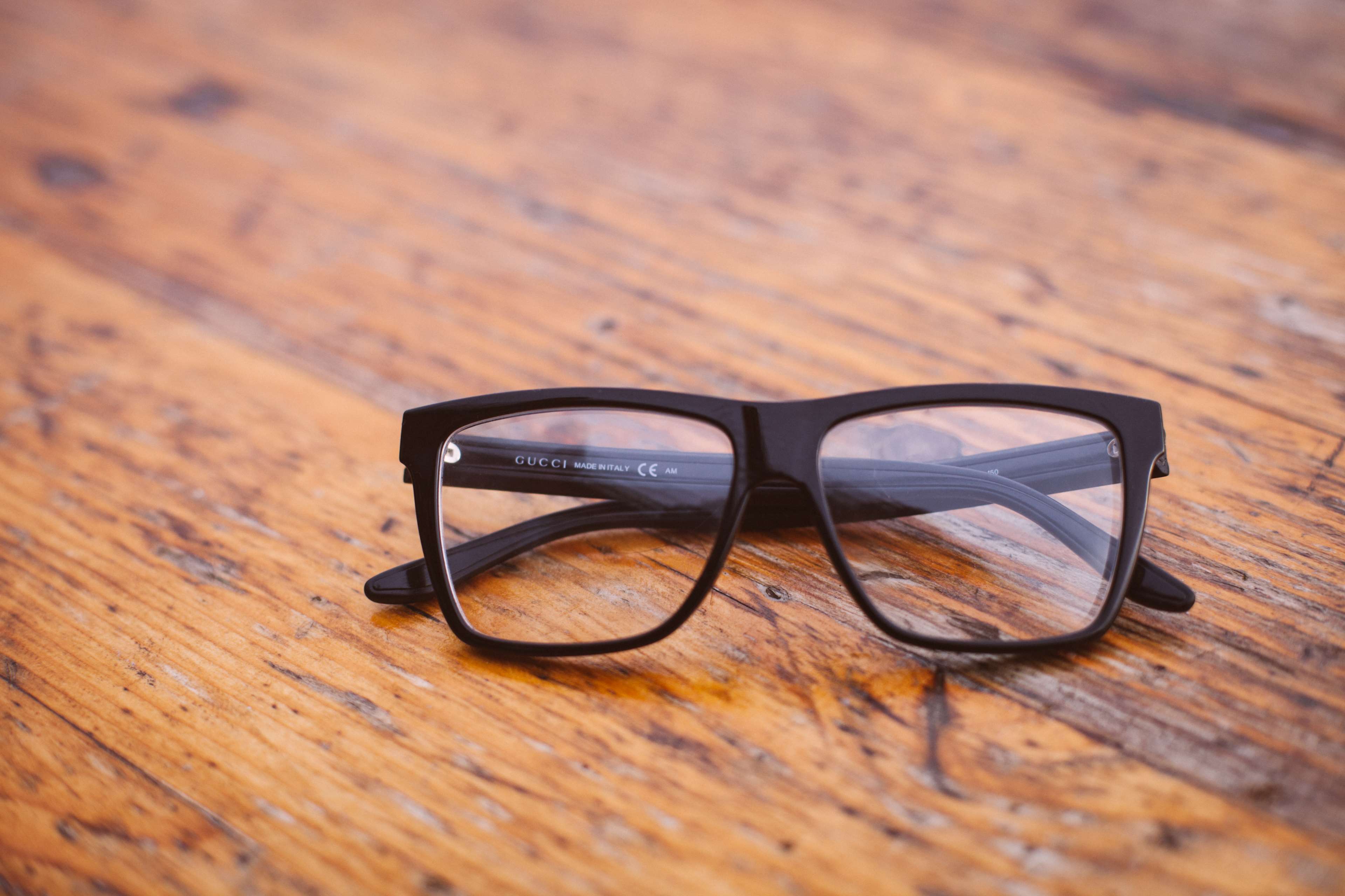 Gucci eyeglasses on a wooden table HD Wallpaper