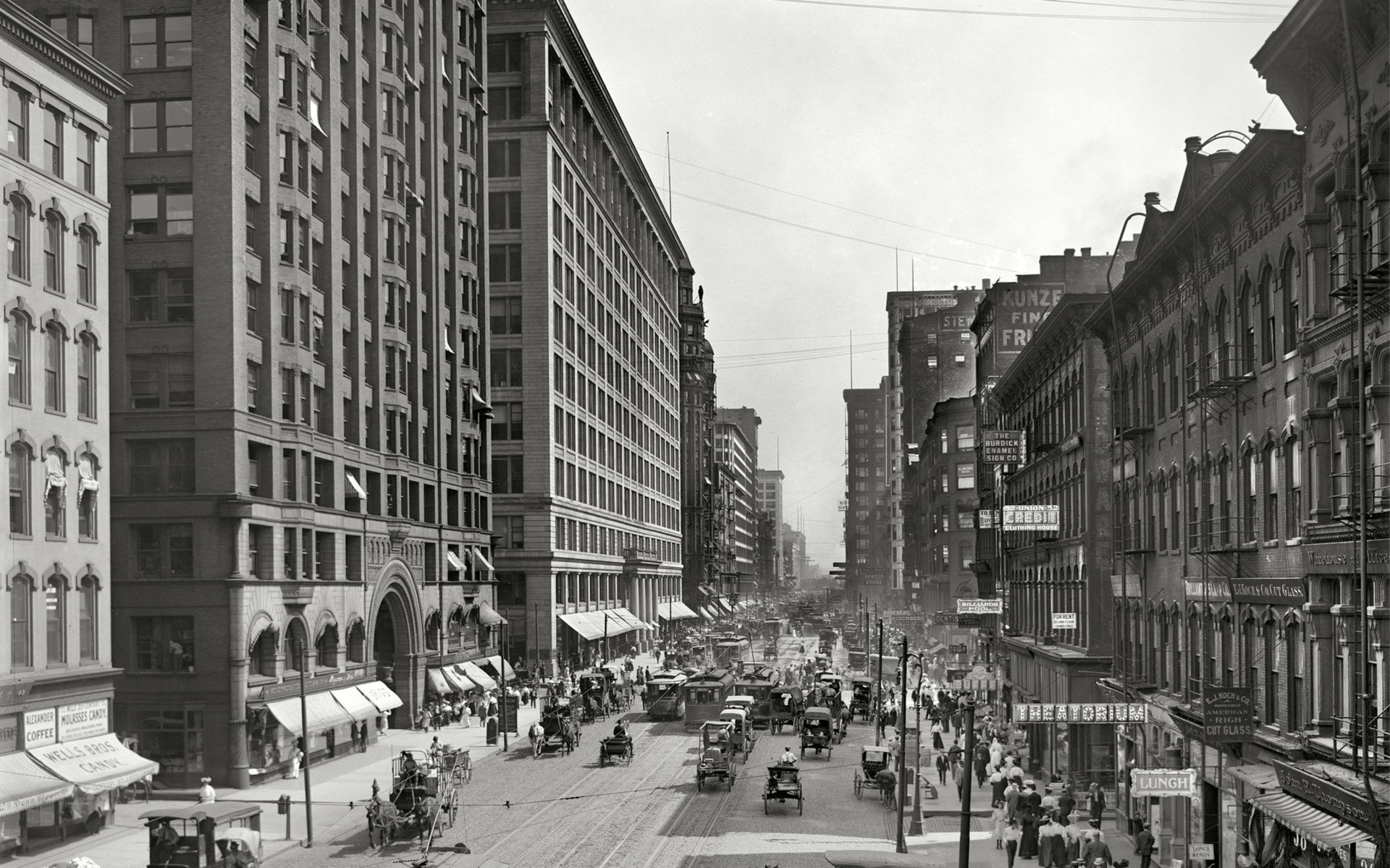 Busy city street with horse-drawn carriages and pedestrians HD Wallpaper