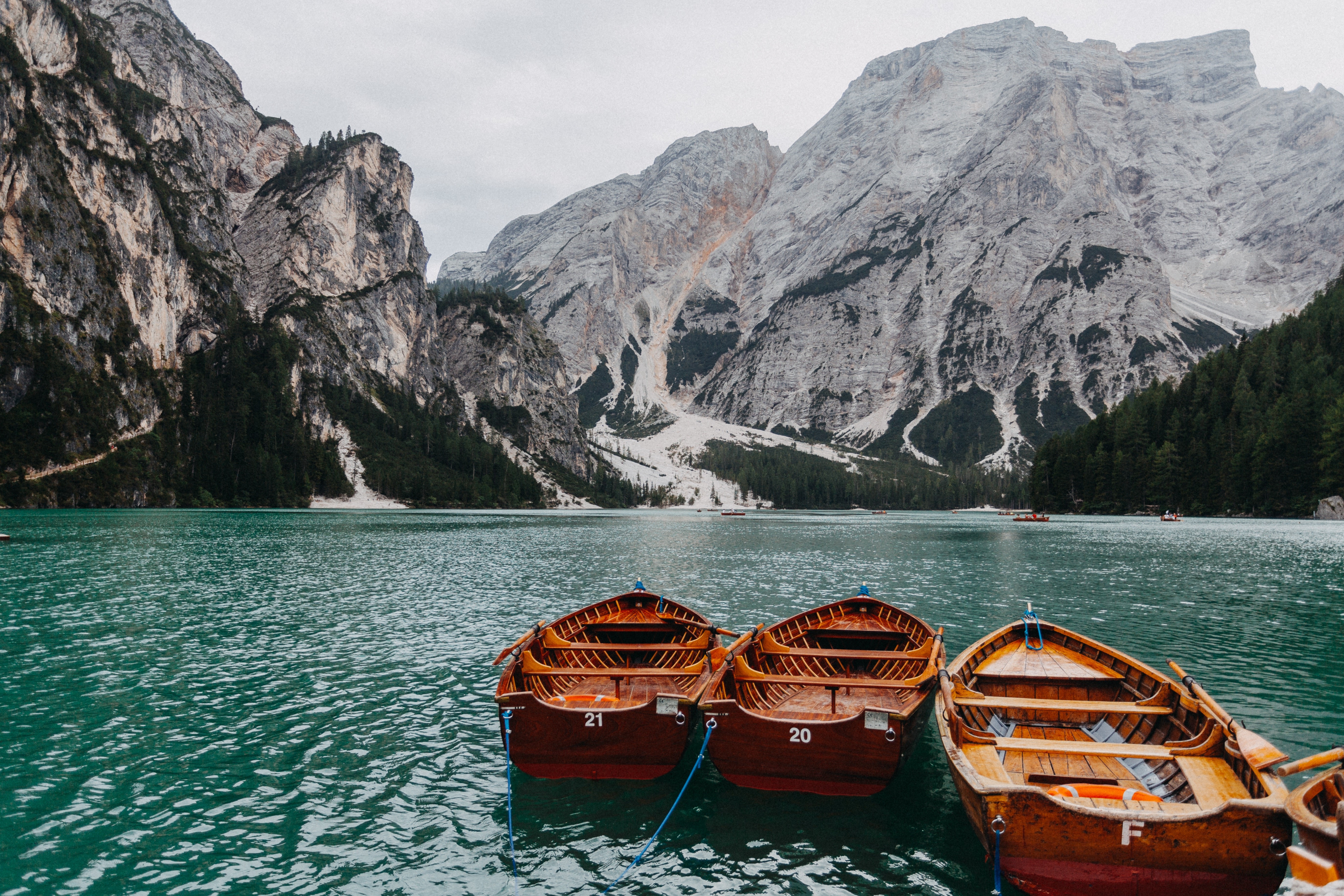 Wooden boats on a turquoise lake with mountains HD Wallpaper