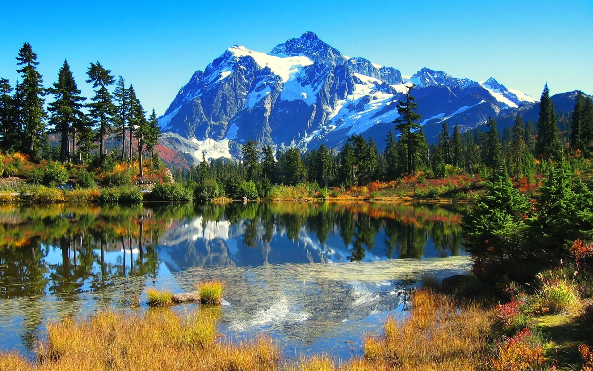 Snow-capped mountains reflected in a lake with autumn trees HD Wallpaper