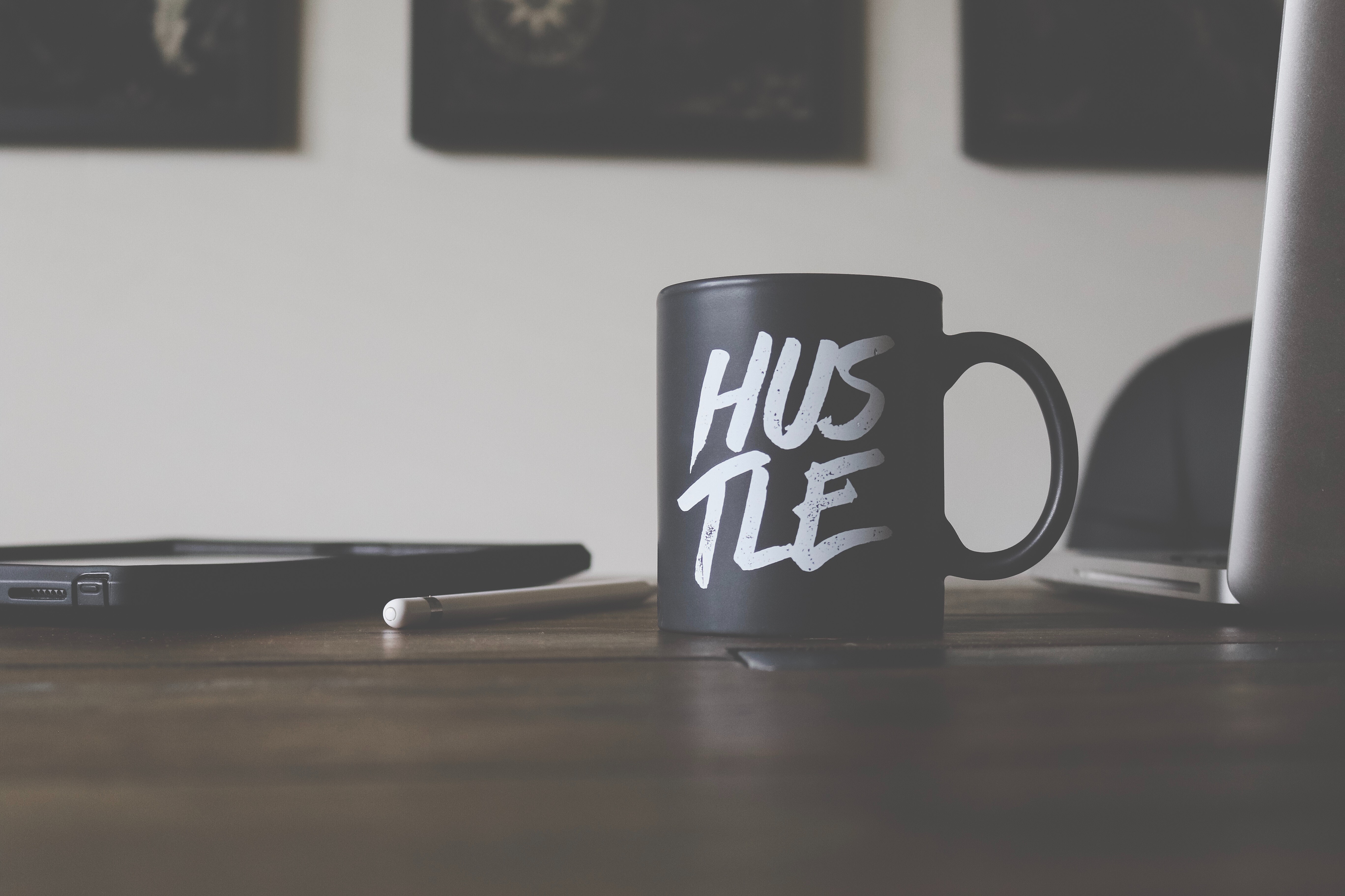 Black mug with "Hustle" inscription on a desk HD Wallpaper